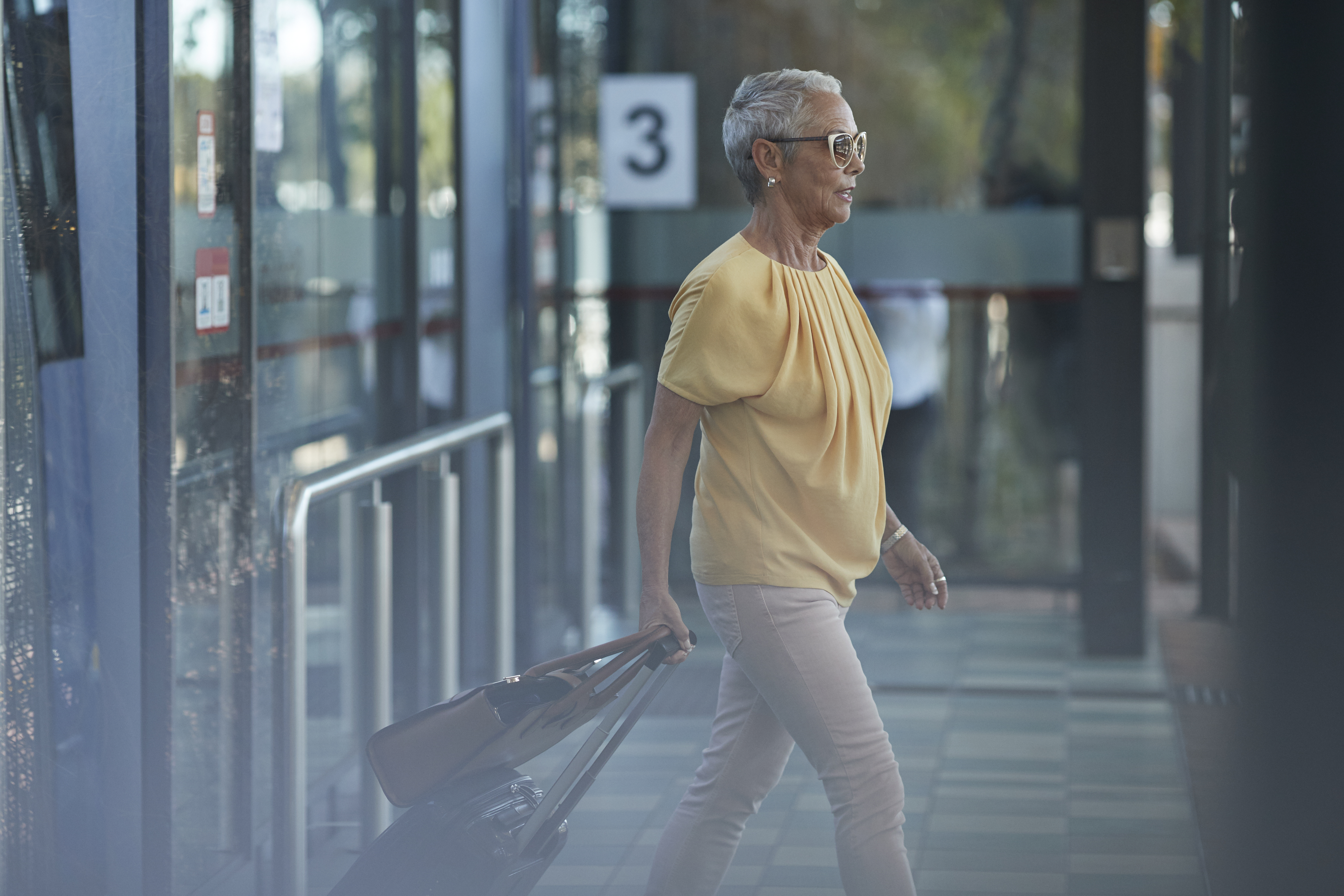 Senior woman walking out of bus, on to public transport platform