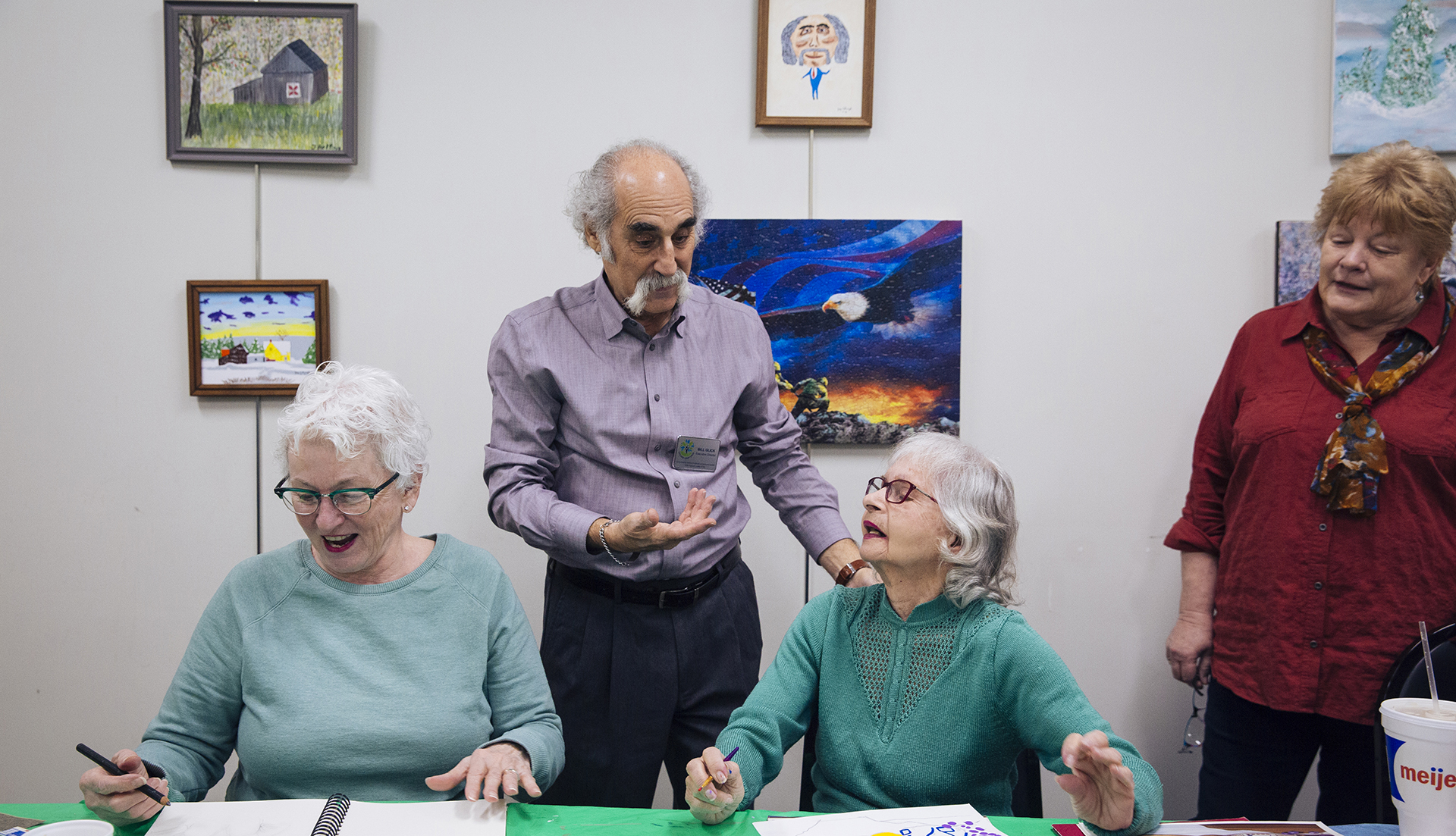 A man speaks with three women at an art class