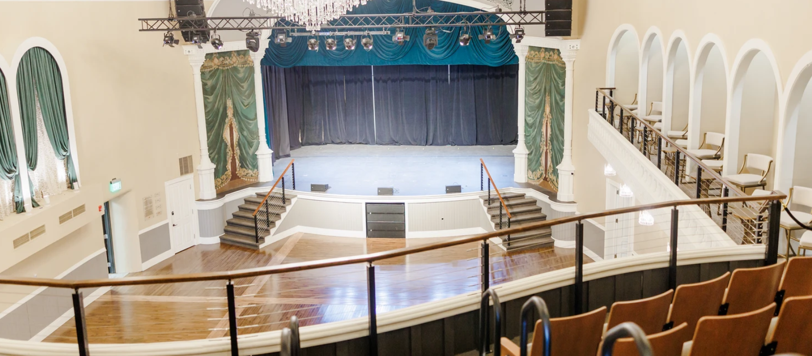 Interior of the Goss Opera House in Watertown showing the stage with green curtains on each side.