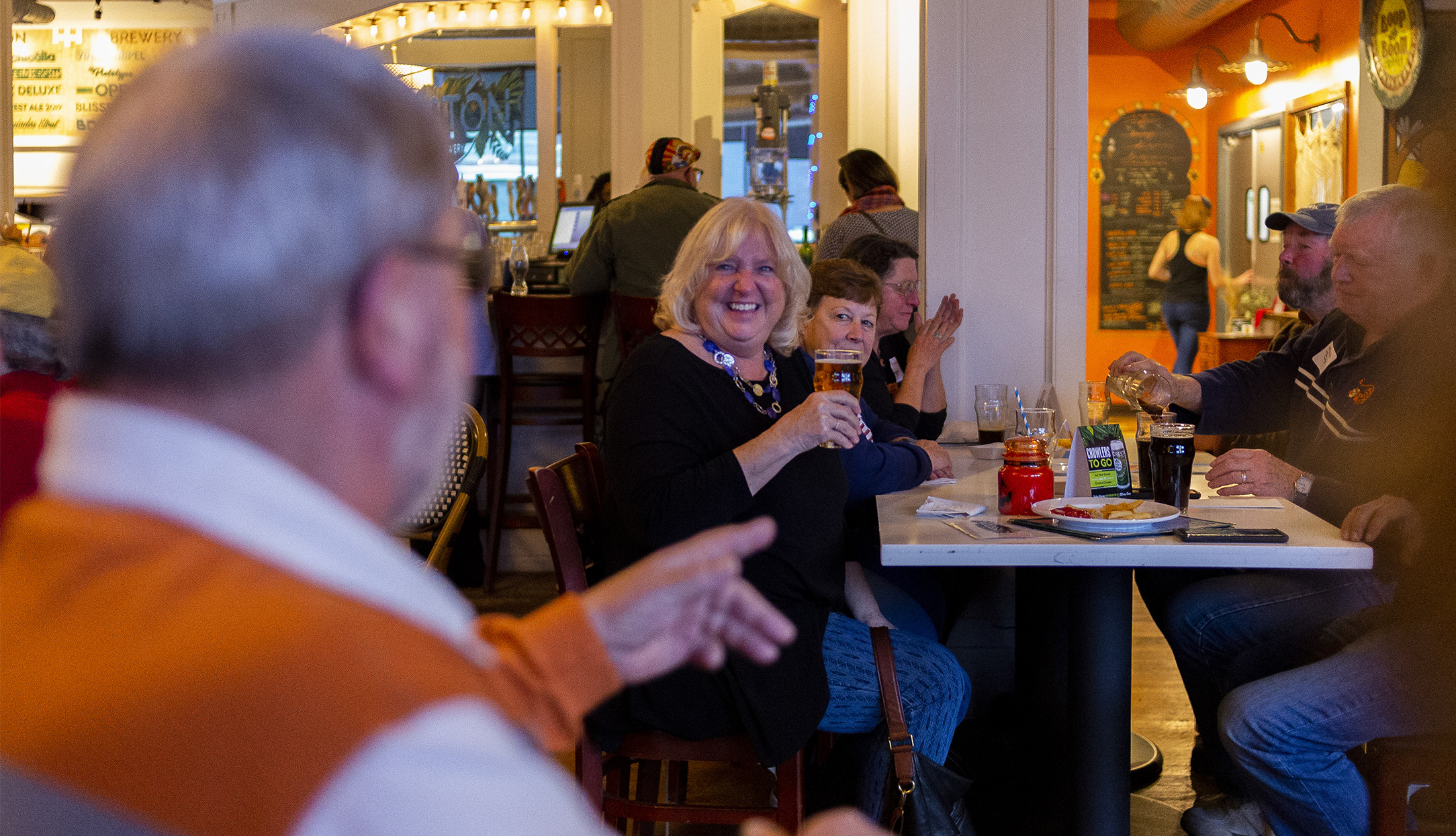 A group of adults enjoy beer and food at a brewery taproom