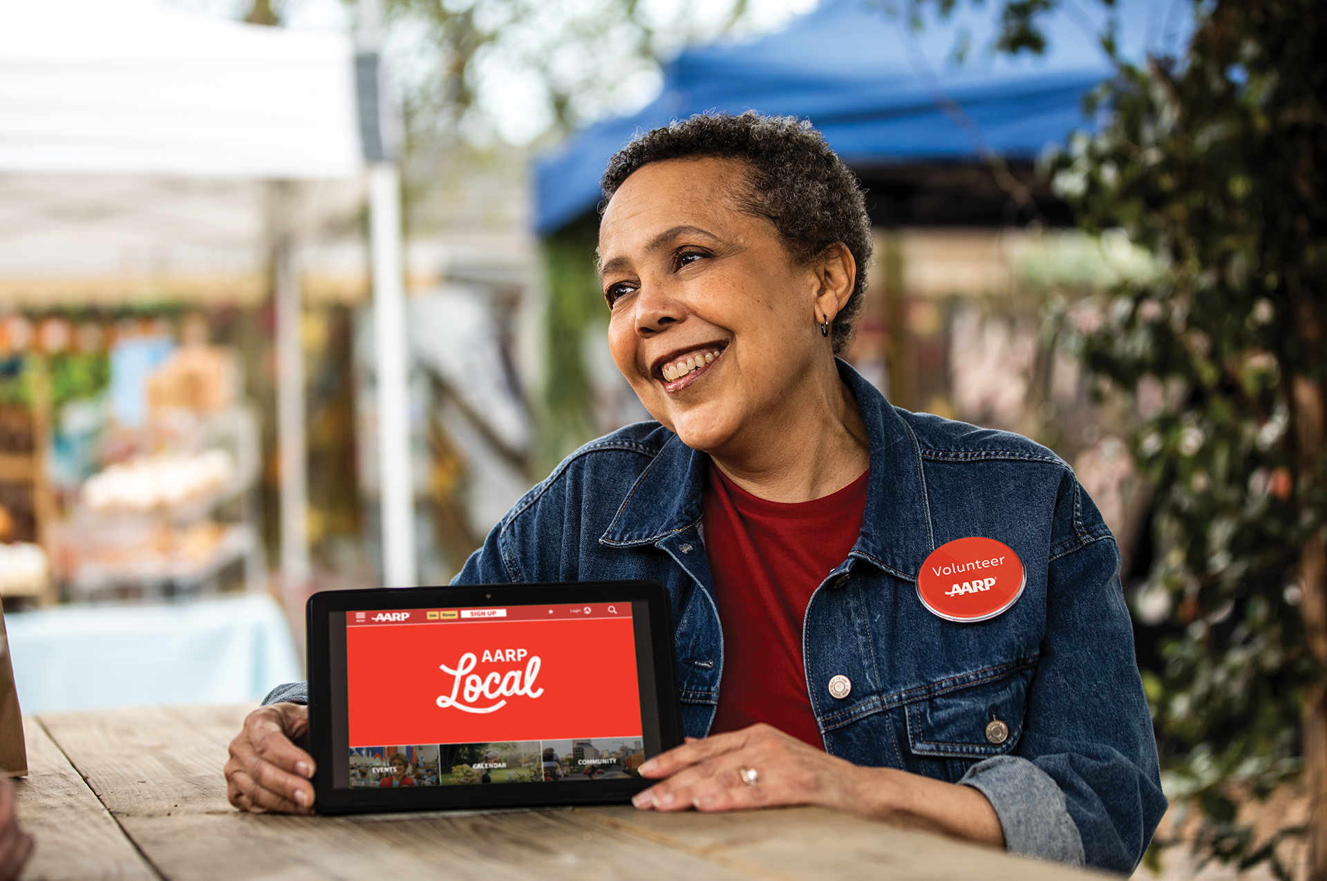 woman holding a tablet with AARP Local on it