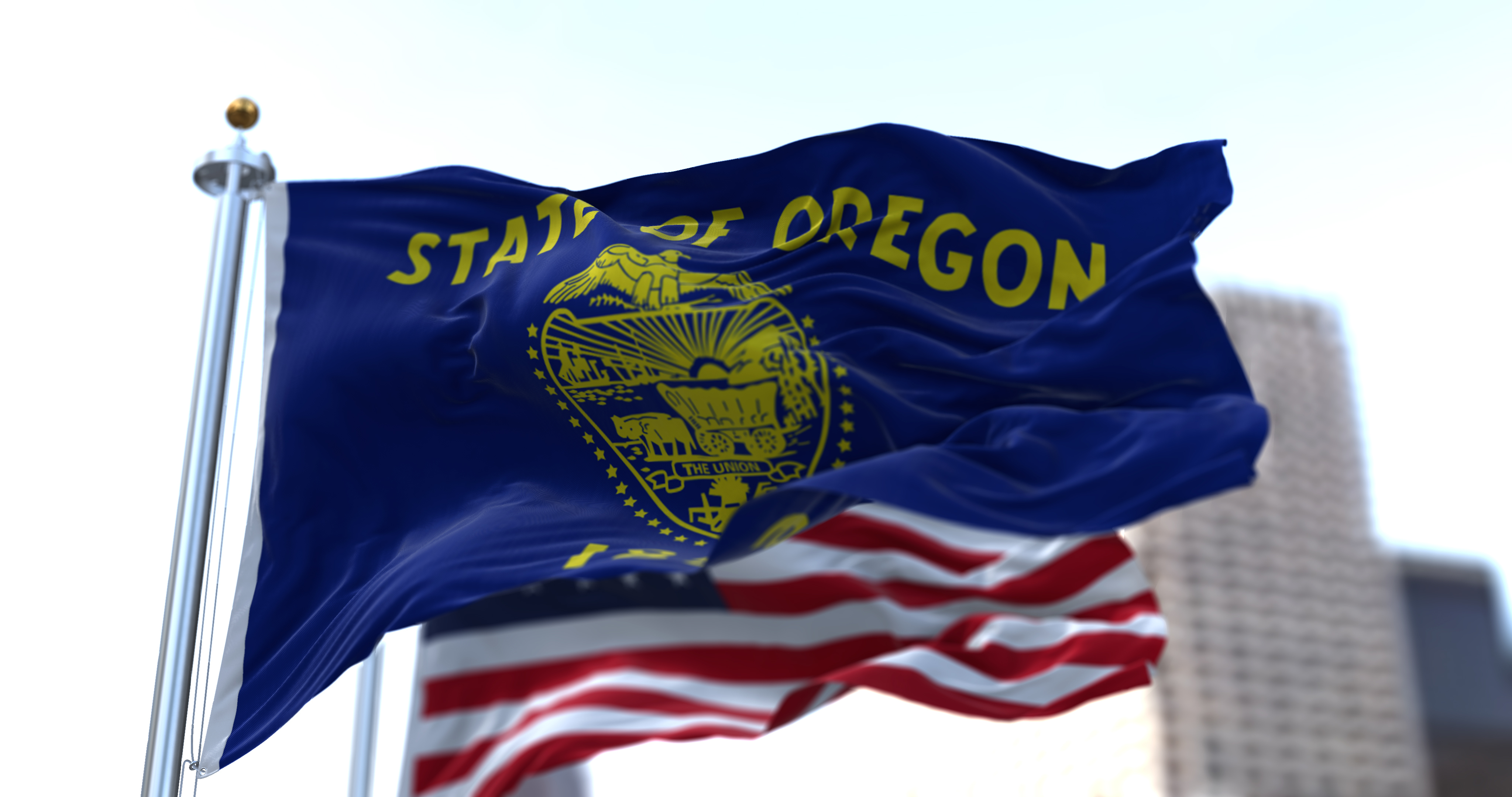 The flags of the Oregon state and United States waving in the wind