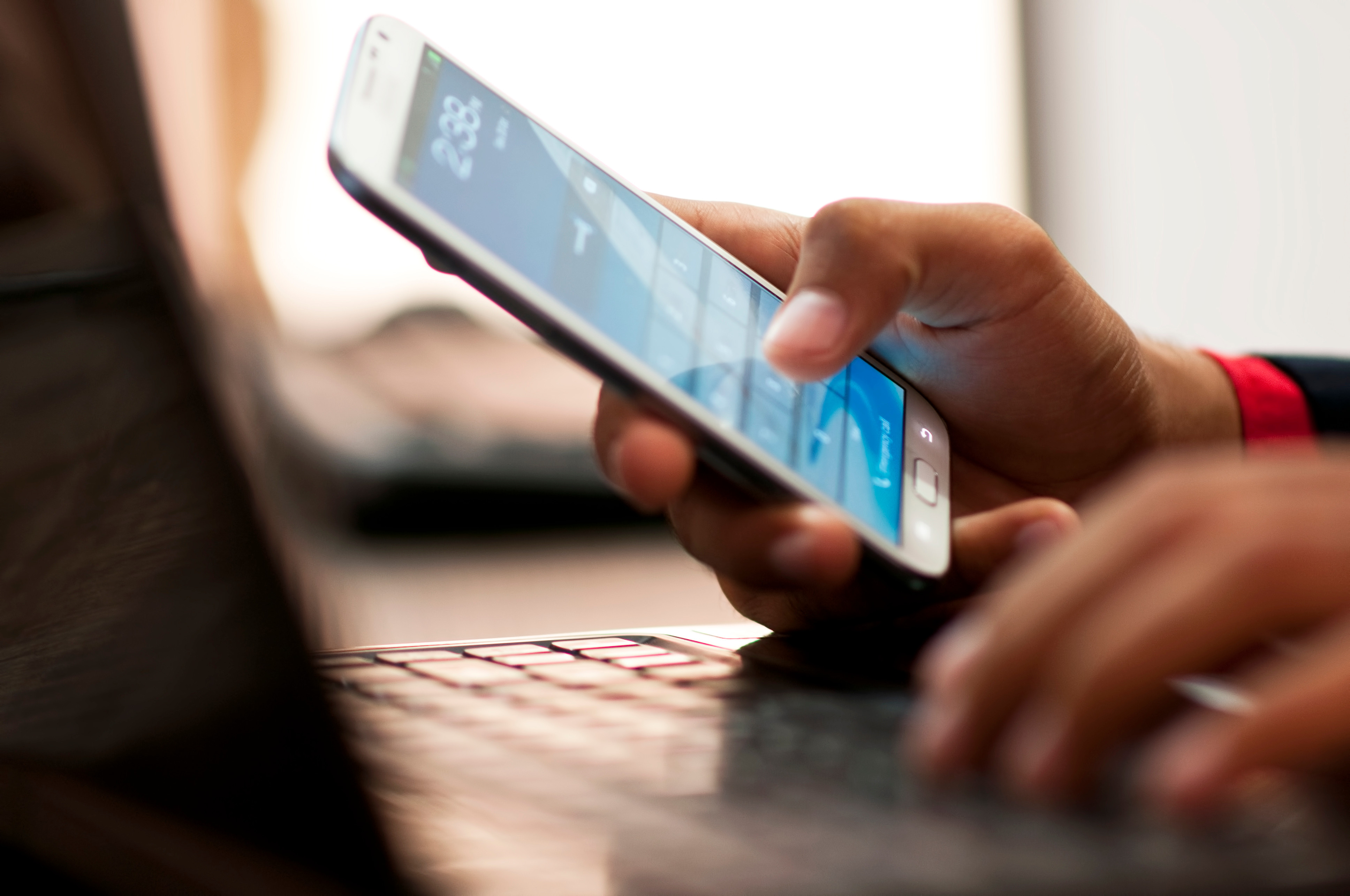 Businessman hand using laptop and mobile phone in office