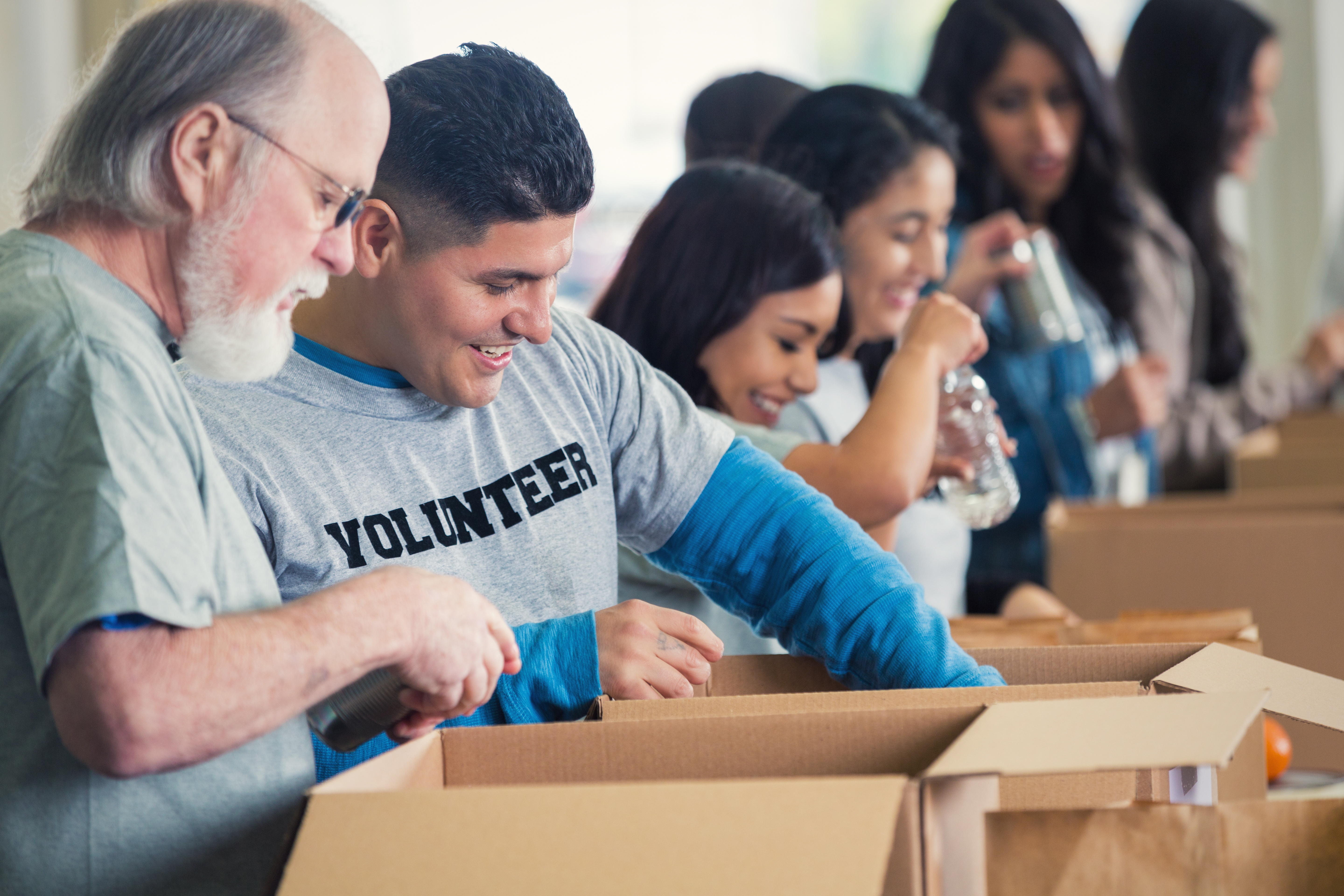 Diverse group of volunteers sorting donated groceries at food bank