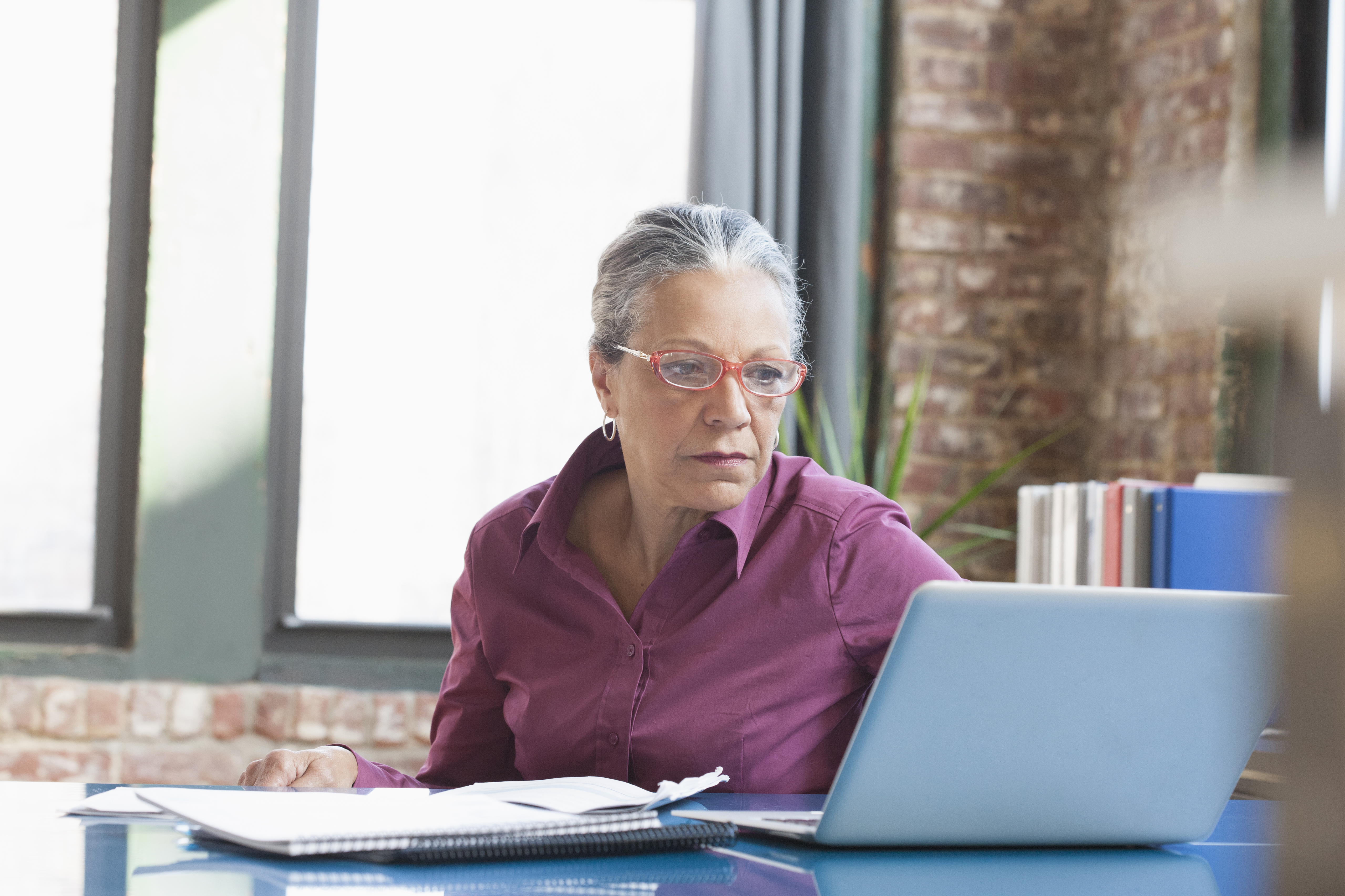 Hispanic businesswoman using laptop in office