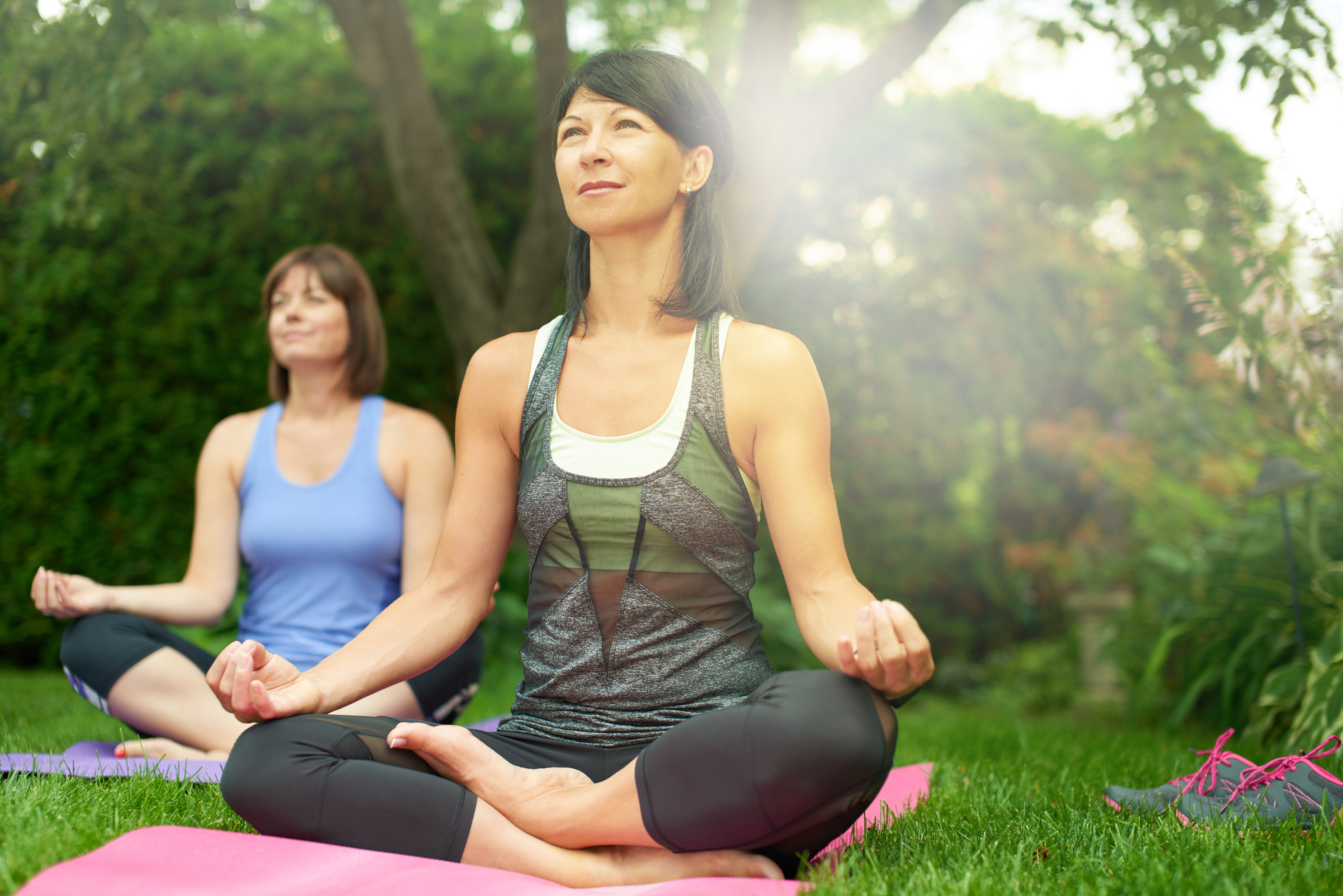 Two mature women keeping fit by doing yoga in the