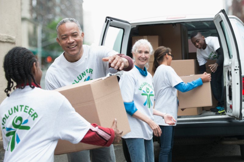 Volunteers passing cardboard boxes from delivery van