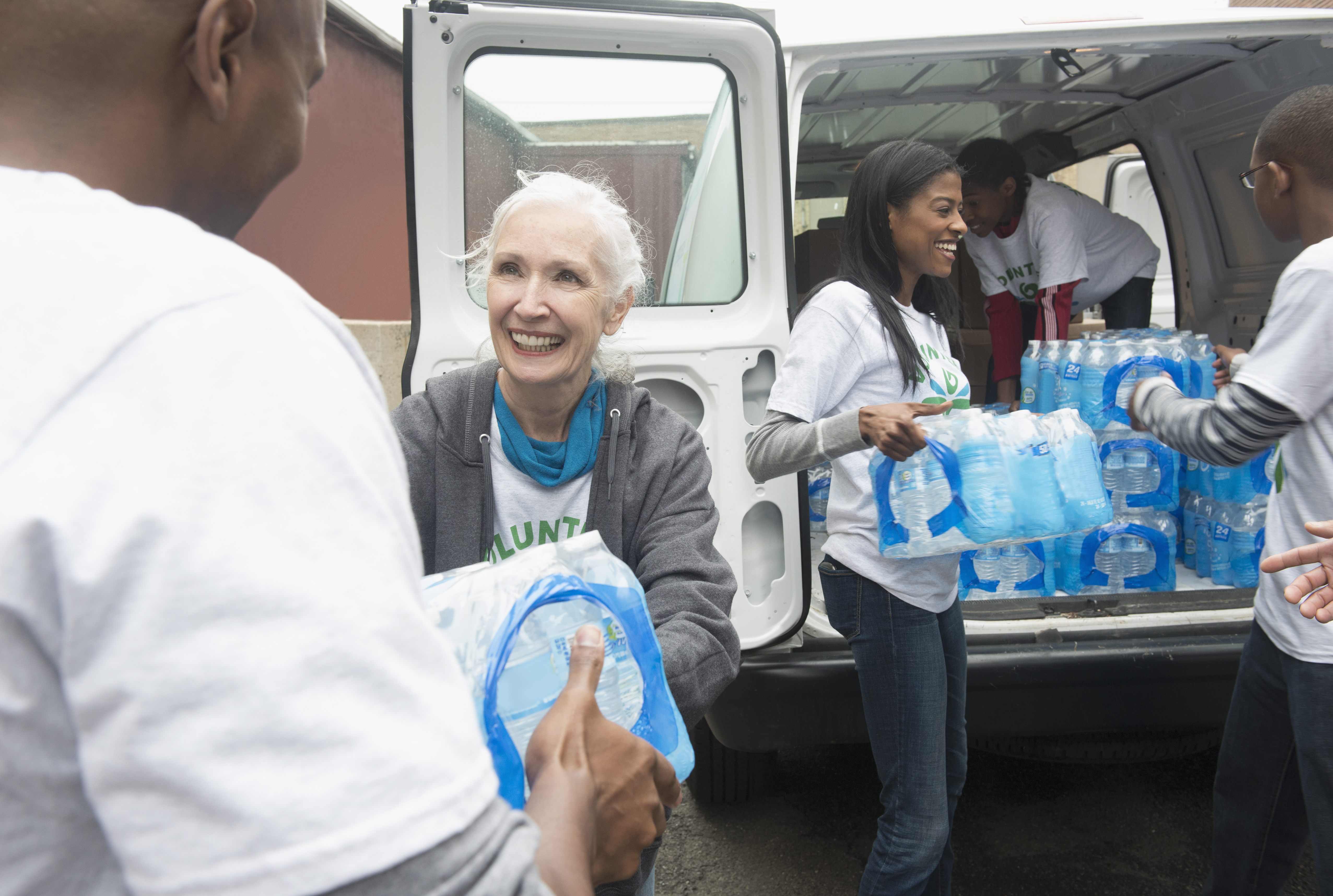 Volunteers passing stacks of bottled water from delivery van