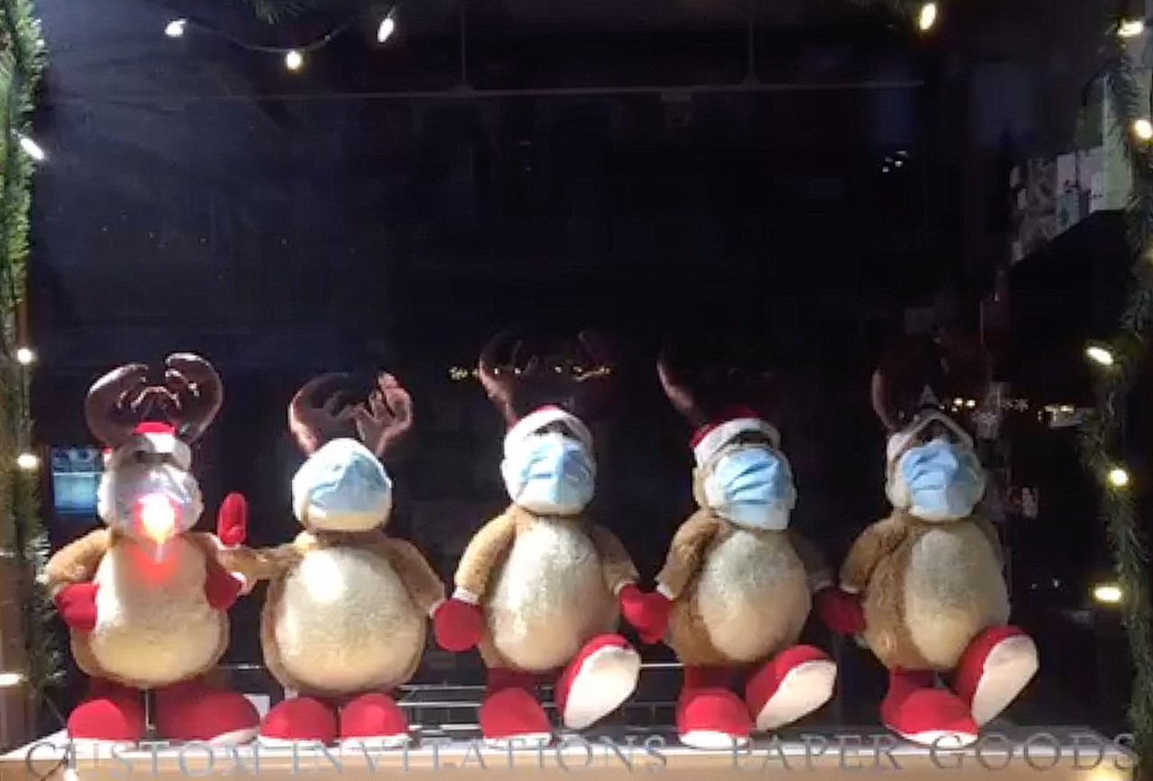 Six festive stuffed reindeers lined up in a window display