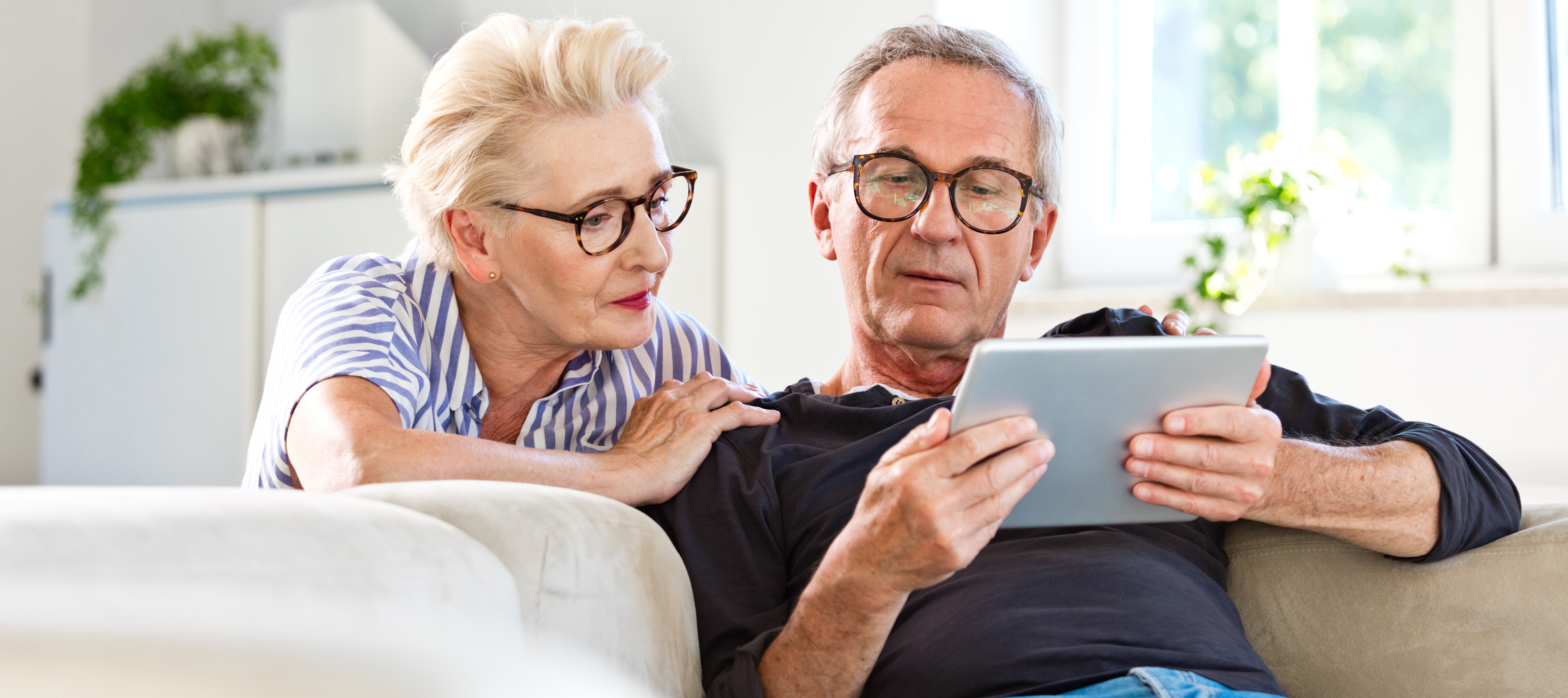 Senior couple watching digital tablet together at home