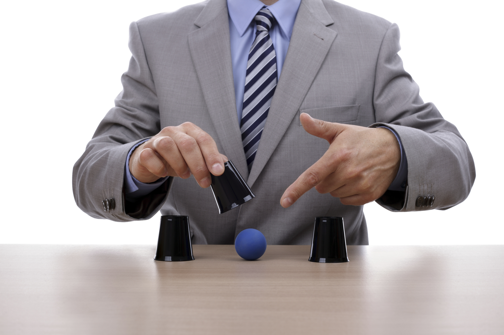 A businessman lifting the center of three cups and pointing