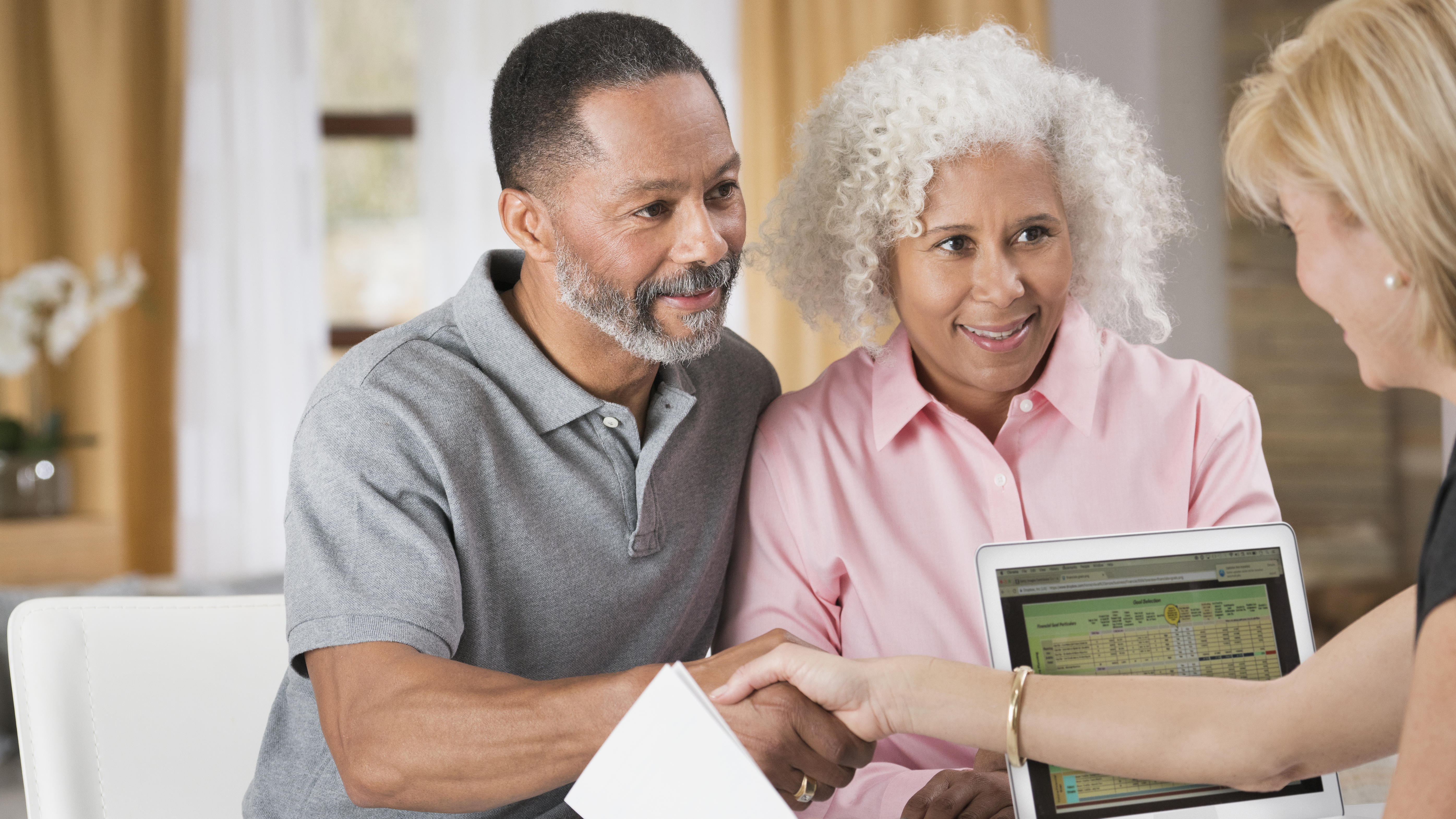 Older couple shaking hands with financial planner