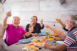 group of elderly men and women at home eating with fun