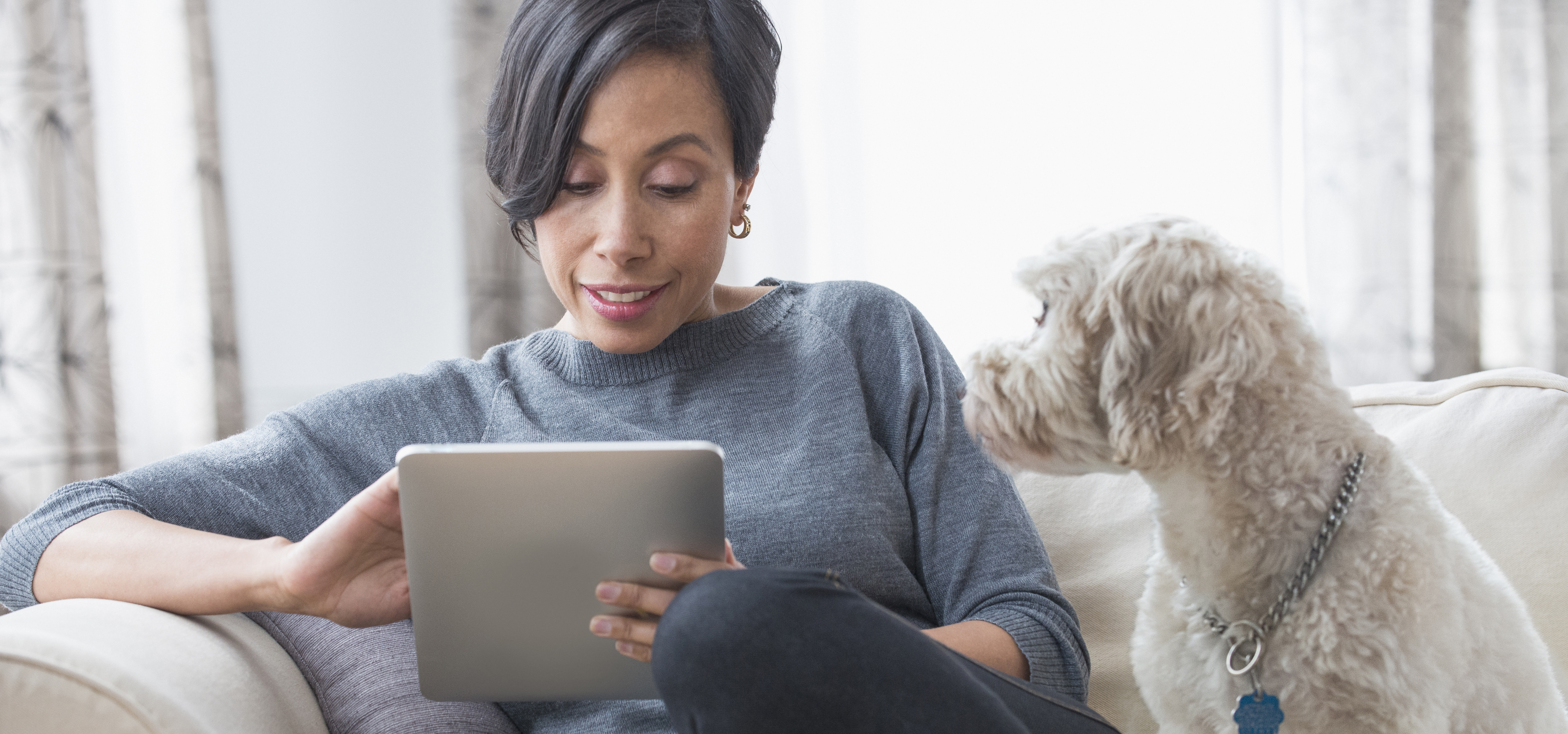 Black woman using digital tablet with dog