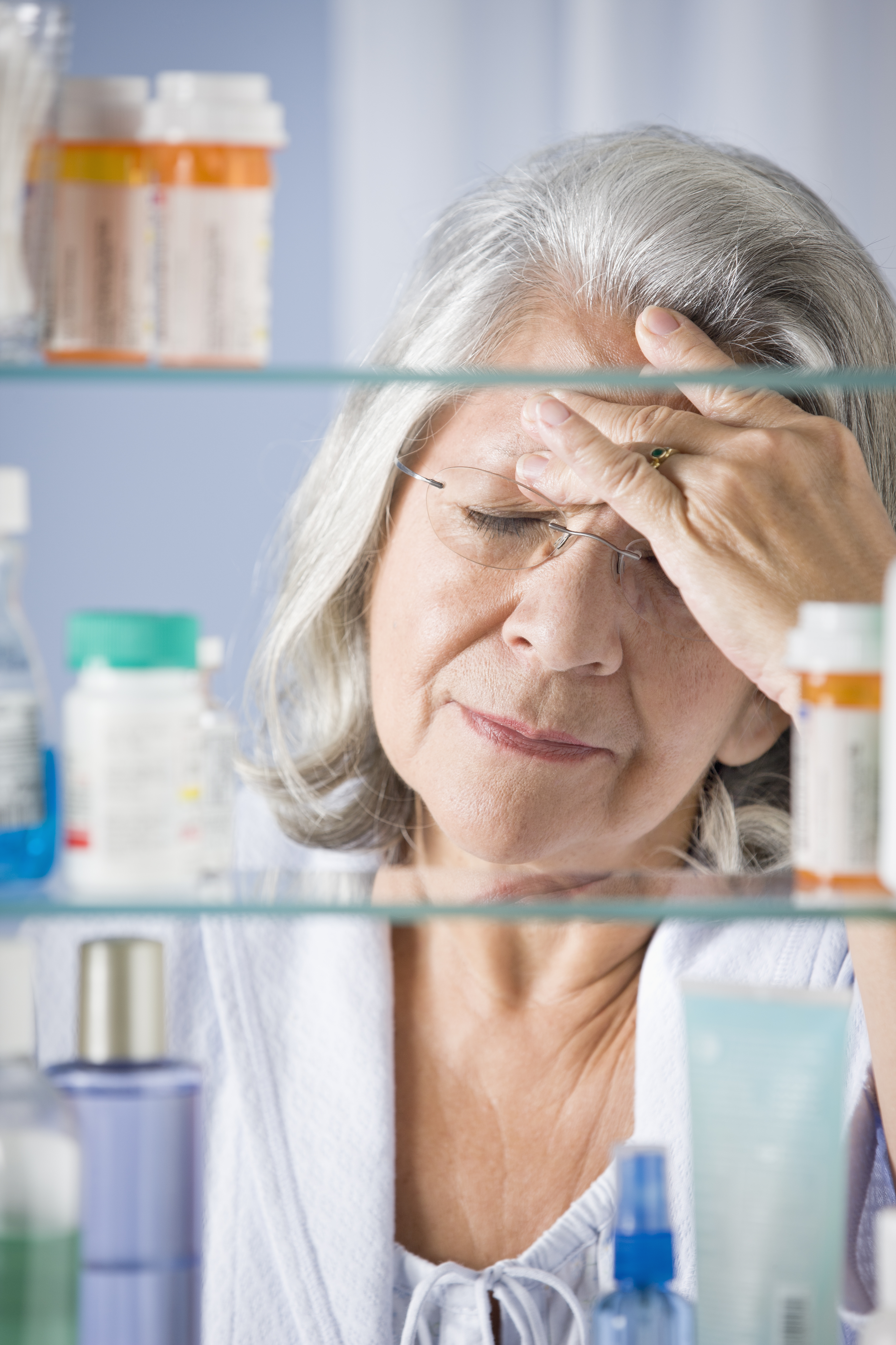 Hispanic woman in bathroom rubbing forehead