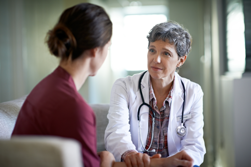 Woman doctor sitting with and facing woman patient