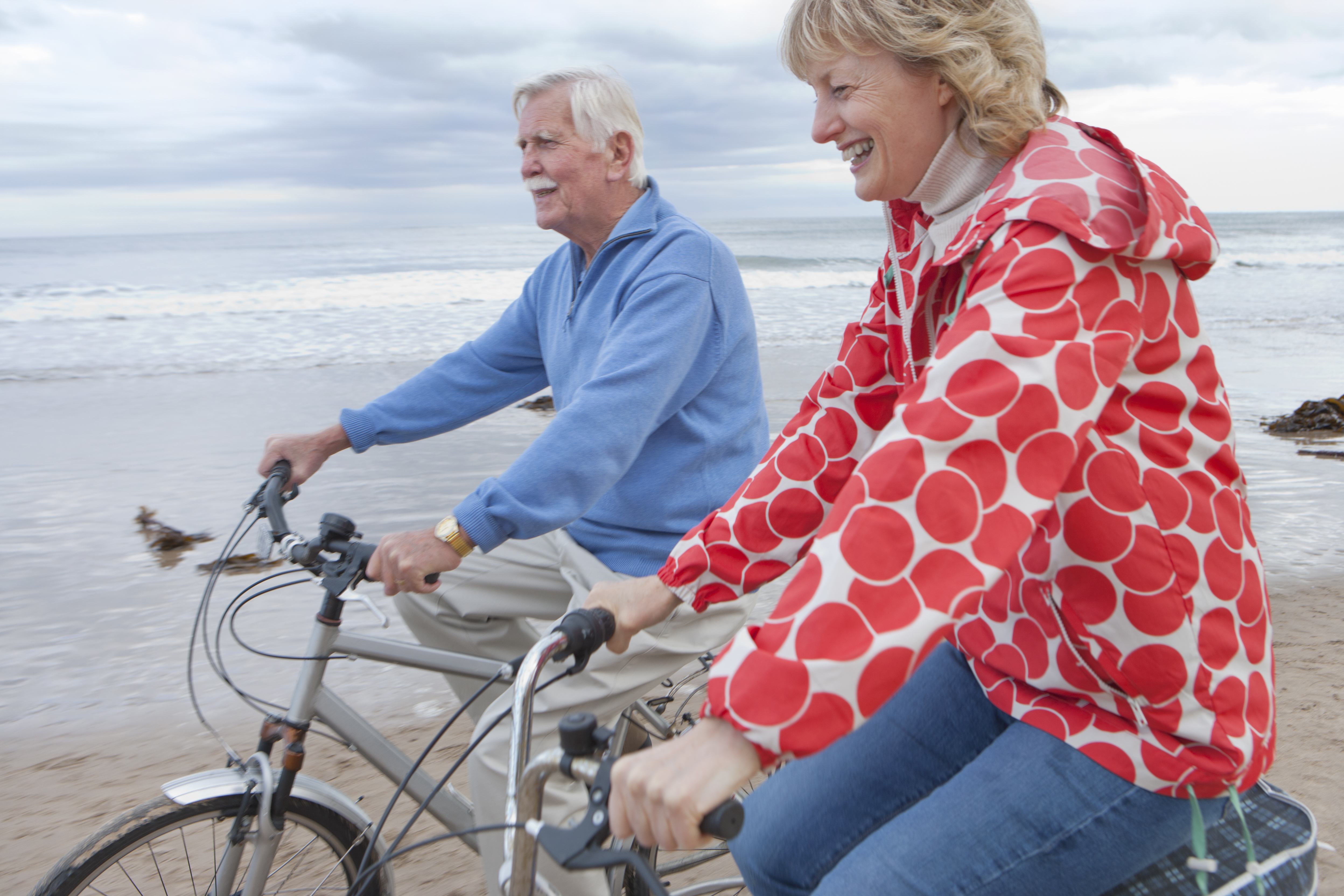 Mature Couple Riding Cycles On Winter Beach Holiday