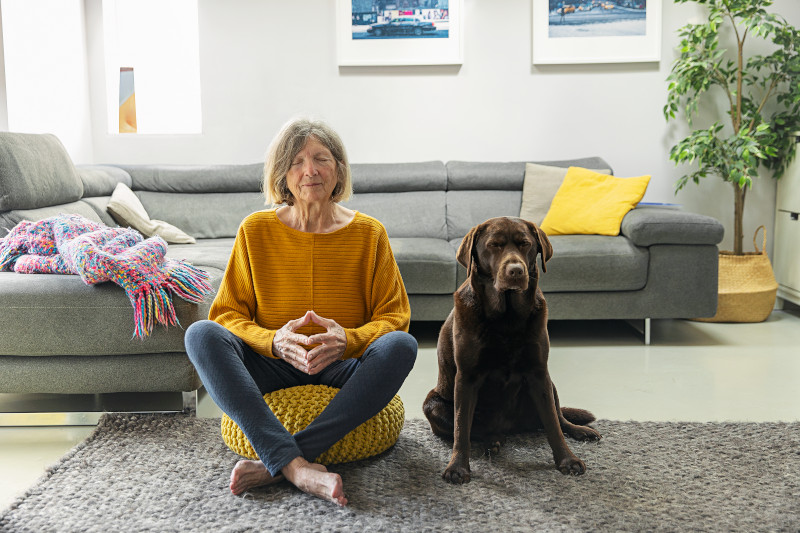 Senior woman meditating at home with her pet dog