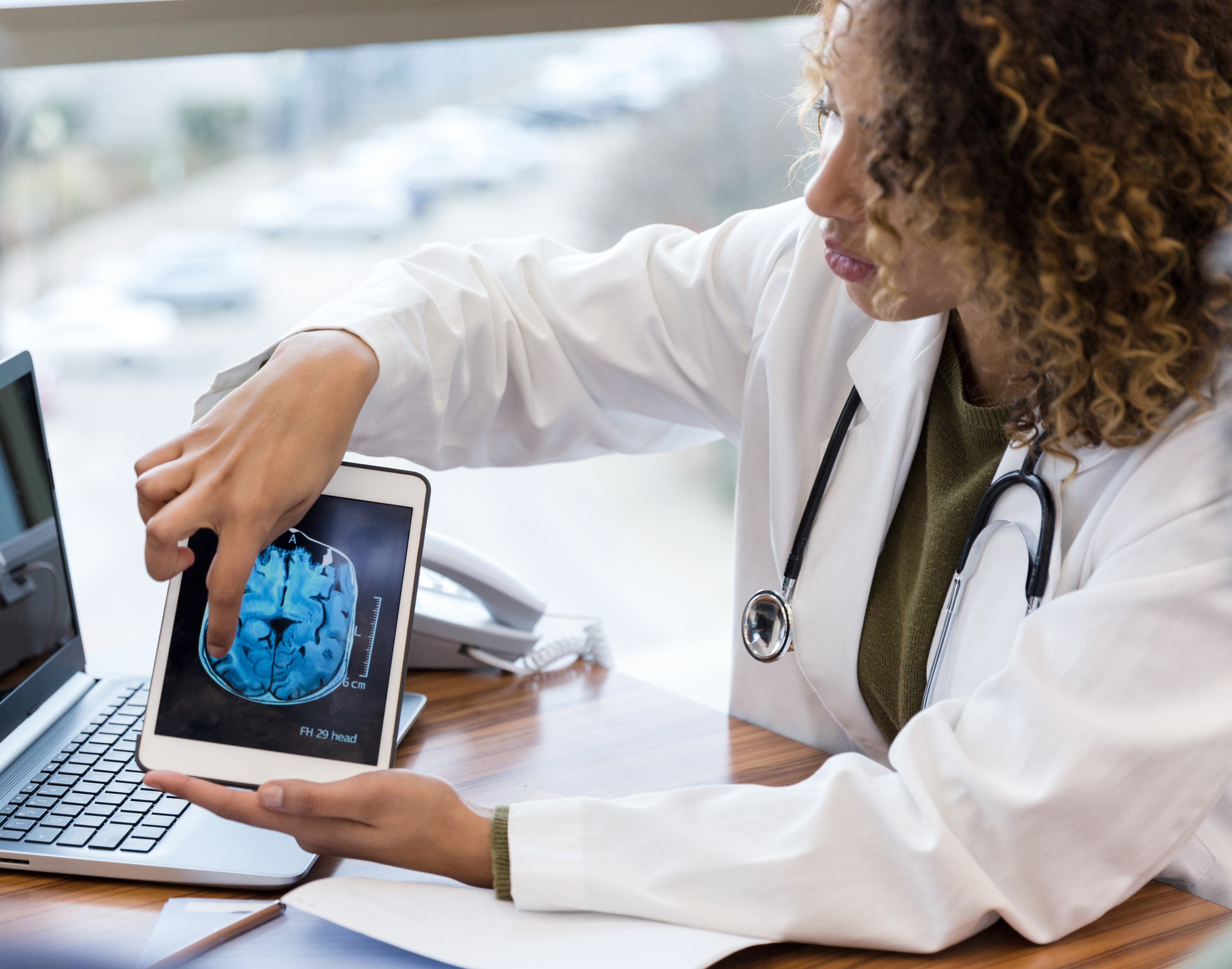 Female doctor explains brain scan to unrecognizable male patient