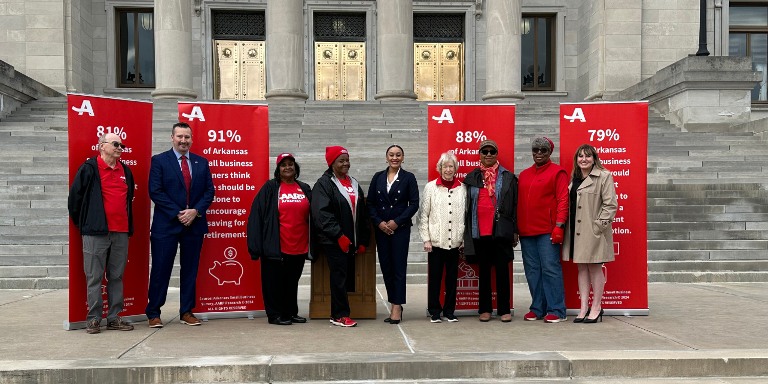 AARP Arkansas staff and volunteers stand on the steps of the State Captiol with banners that talk about Arkansas Save legislation.