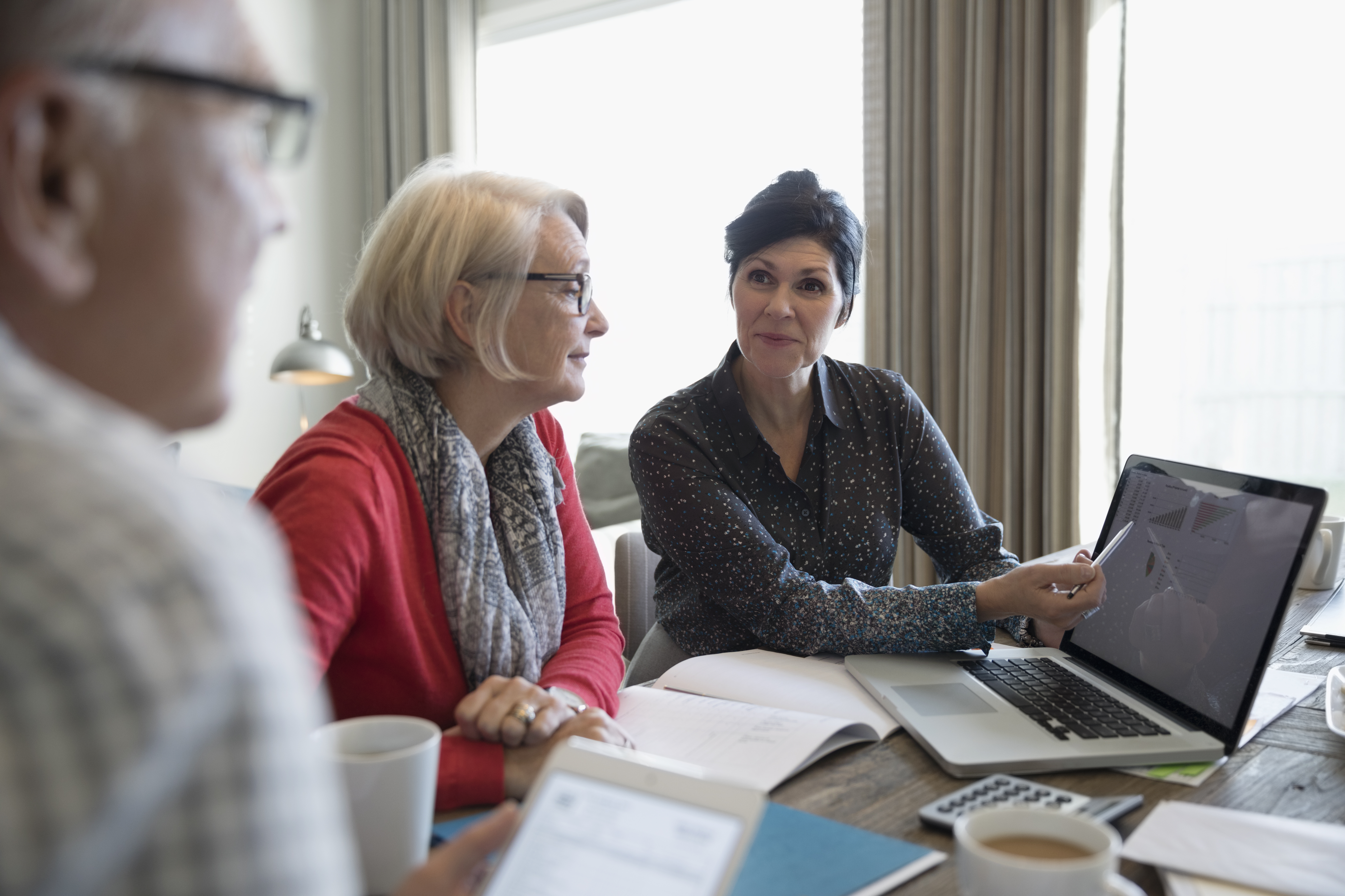 Financial advisor with laptop meeting with senior couple in dining room