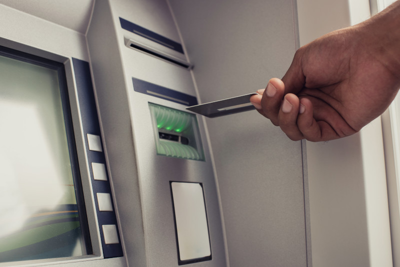 Close up of unrecognizable person with credit card on ATM.