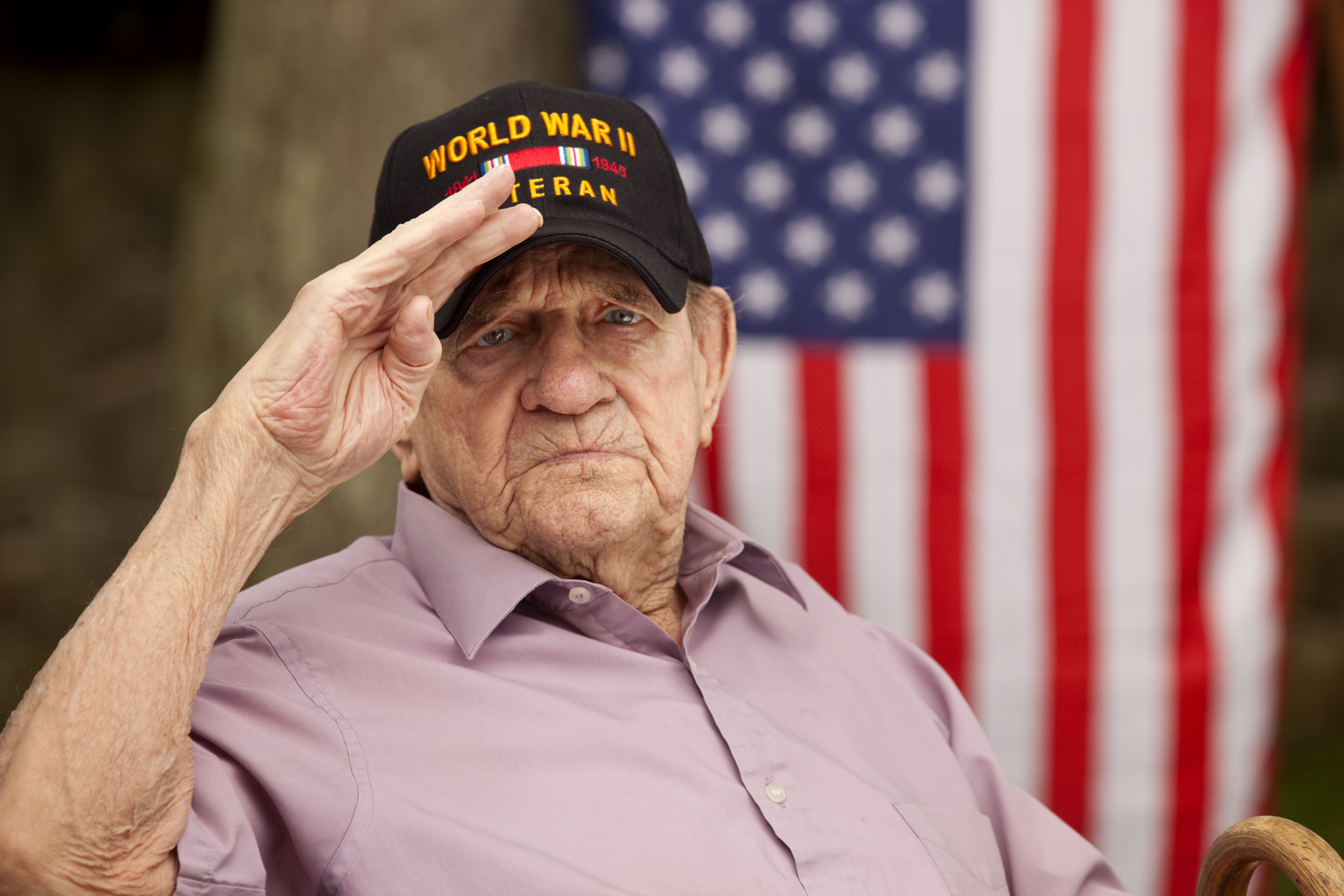 World War Two, Veteran wearing baseball cap with text, "World War Two Veteran". Saluting
