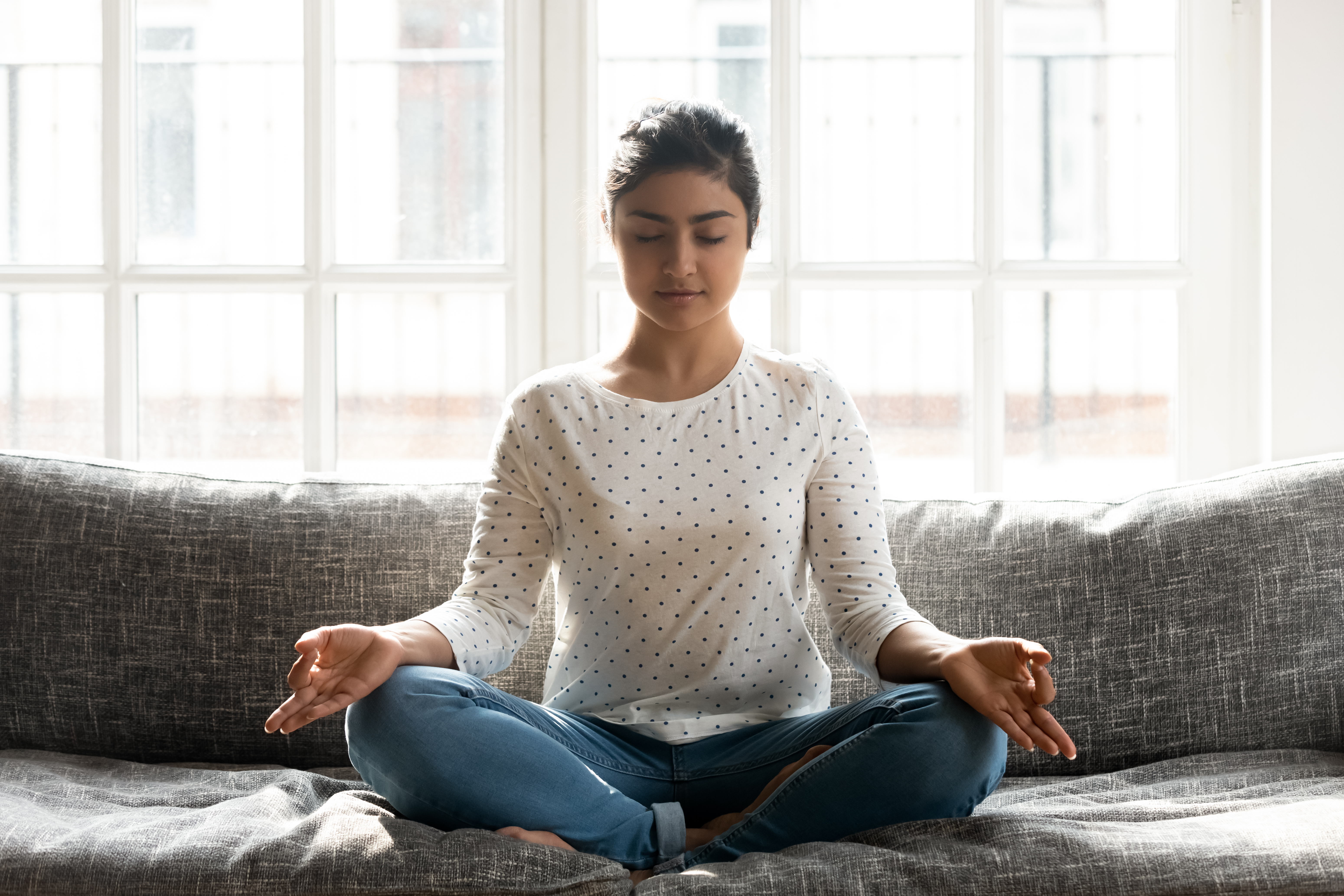 Mindful young indian woman doing breathing yoga exercises alone.