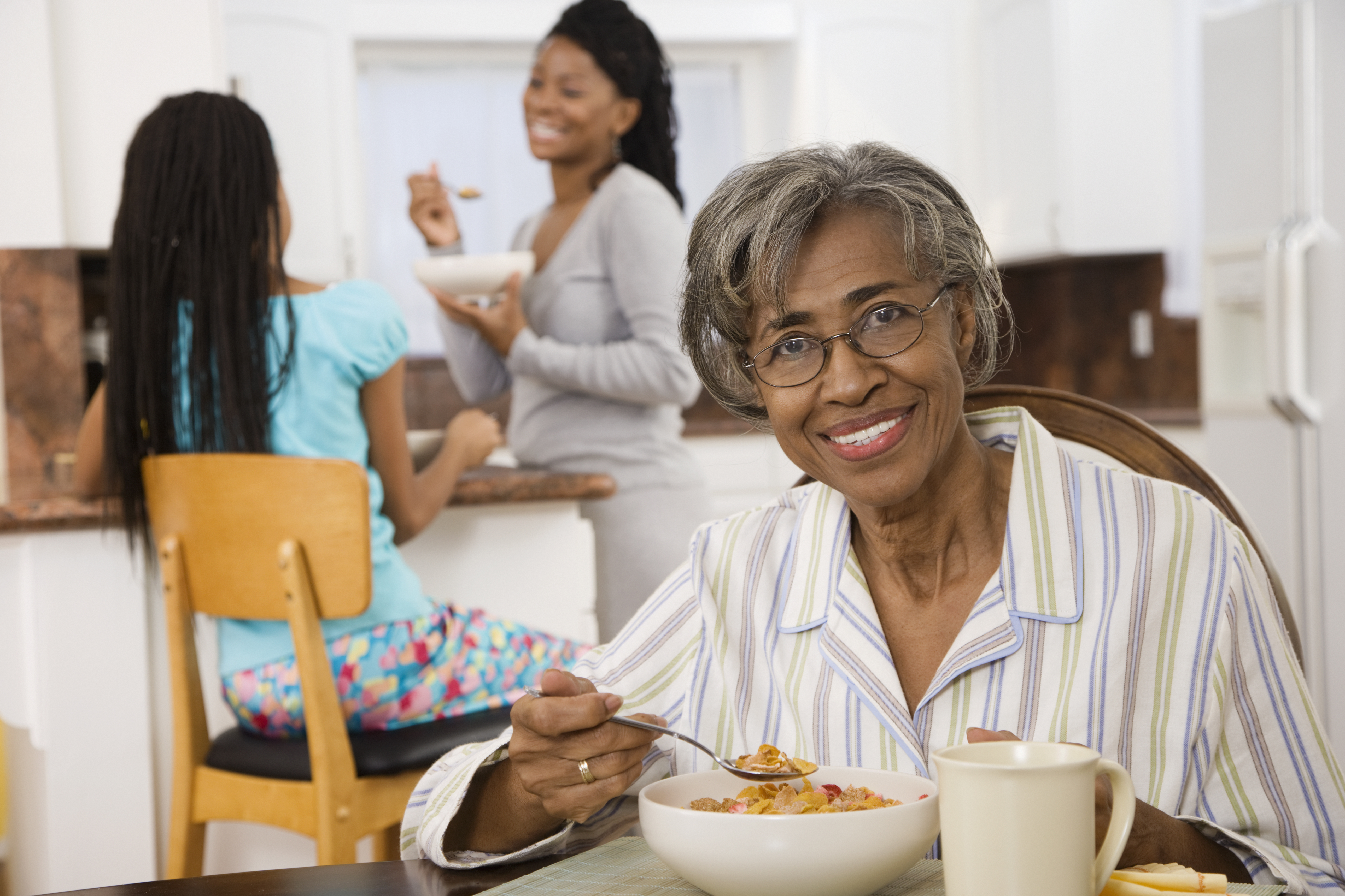 Senior African woman eating breakfast in kitchen