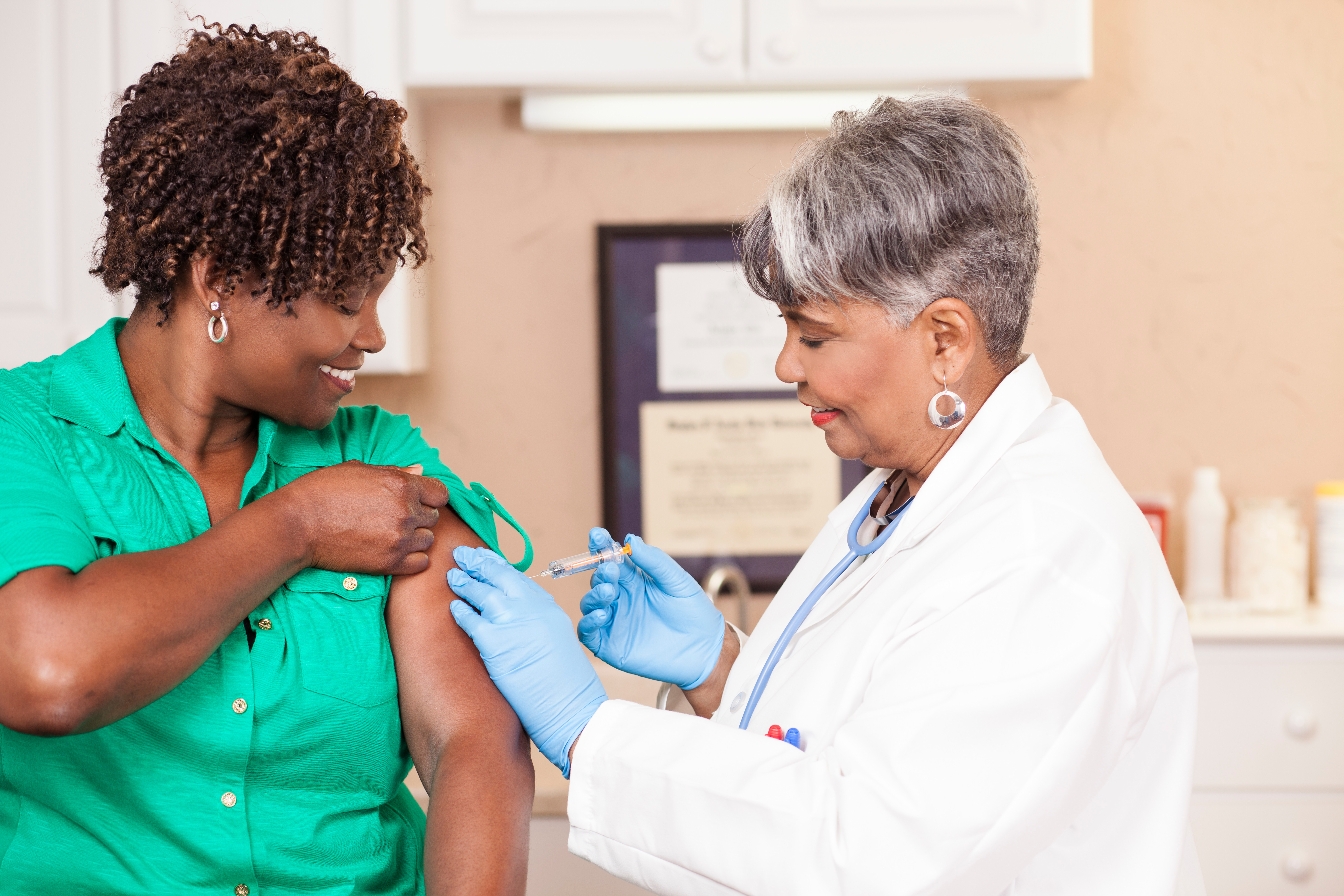 Doctor or nurse gives flu vaccine to patient at clinic.