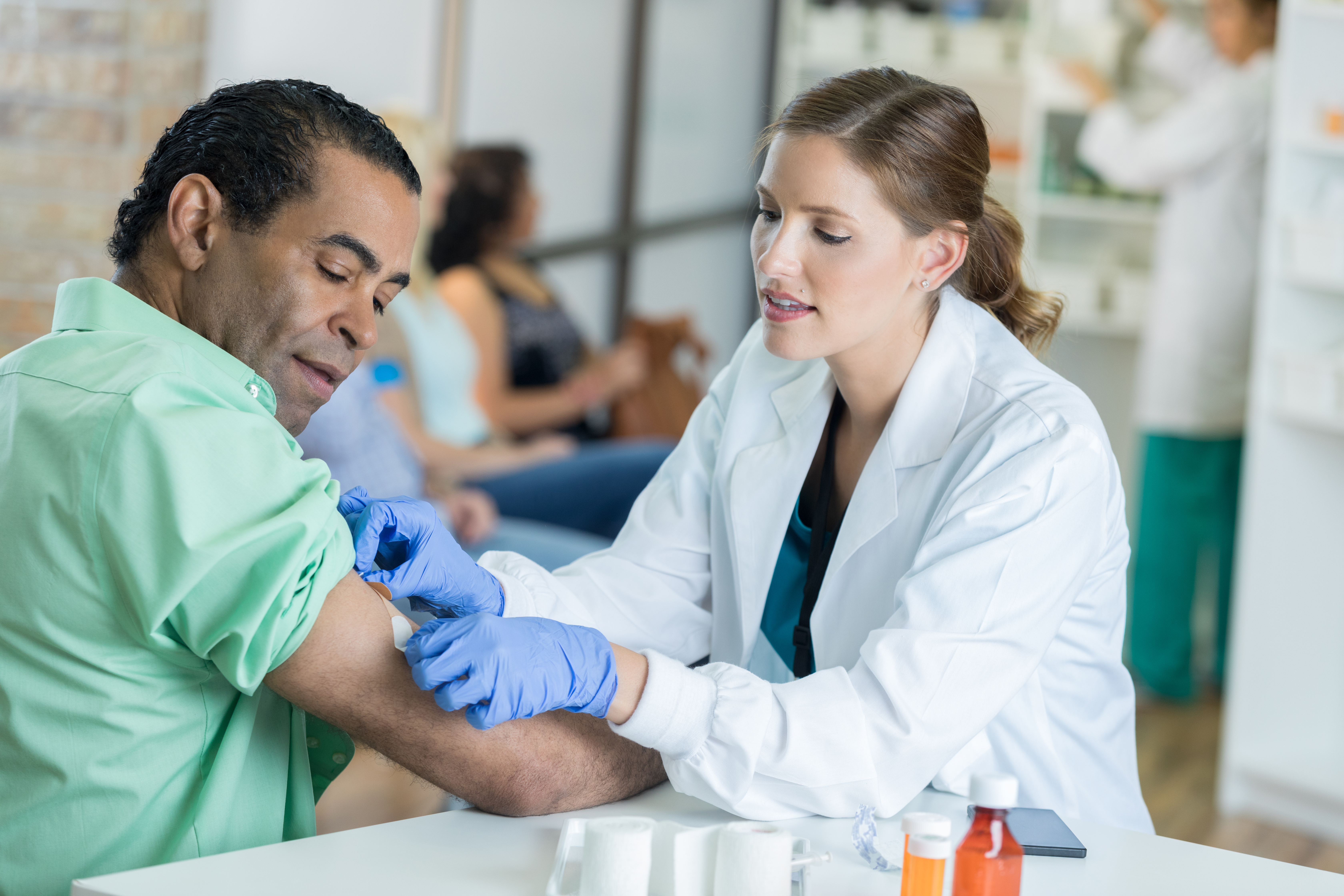 Caring healthcare professional places bandage on man's arm