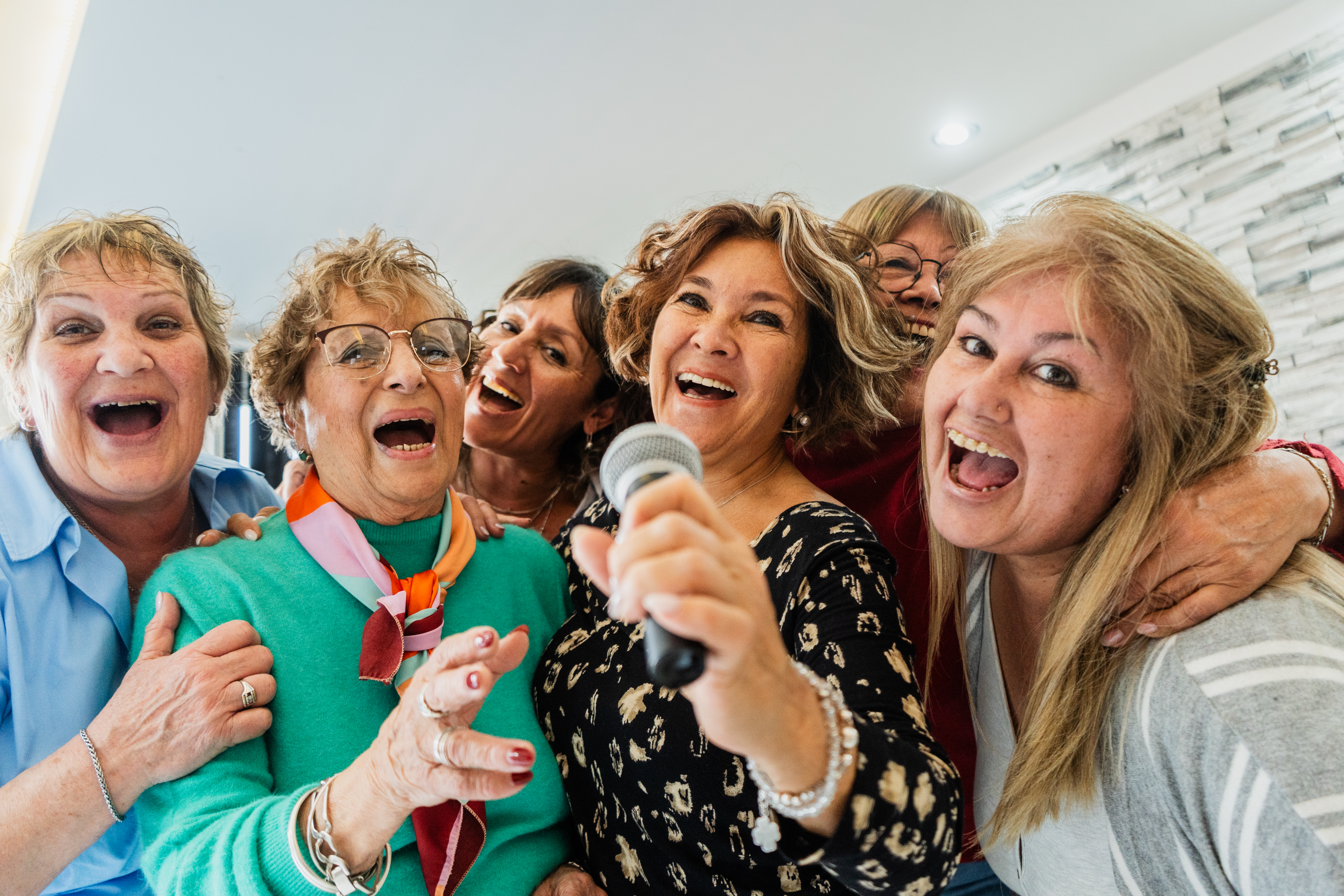 Portrait of senior friends having fun singing karaoke at home