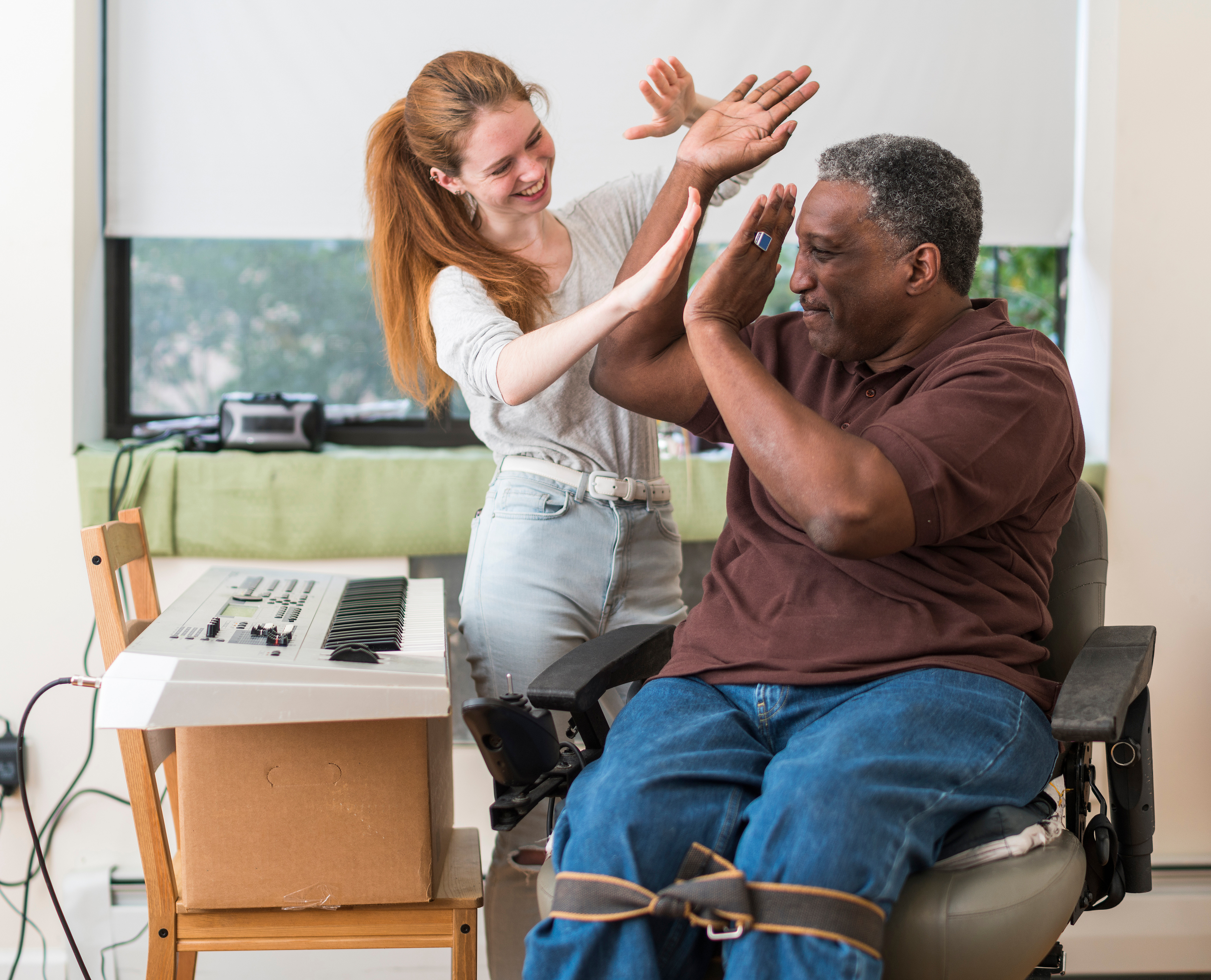 High Five! The disabled veteran, black man, teaching the White teenager girl to play piano keyboard.