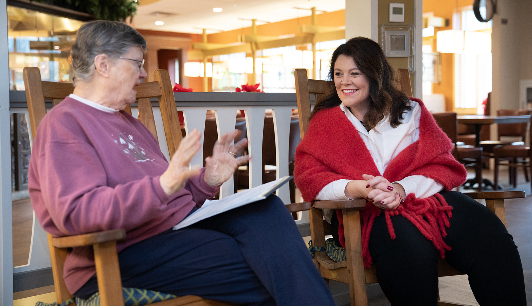 Two women sit in chairs talking together