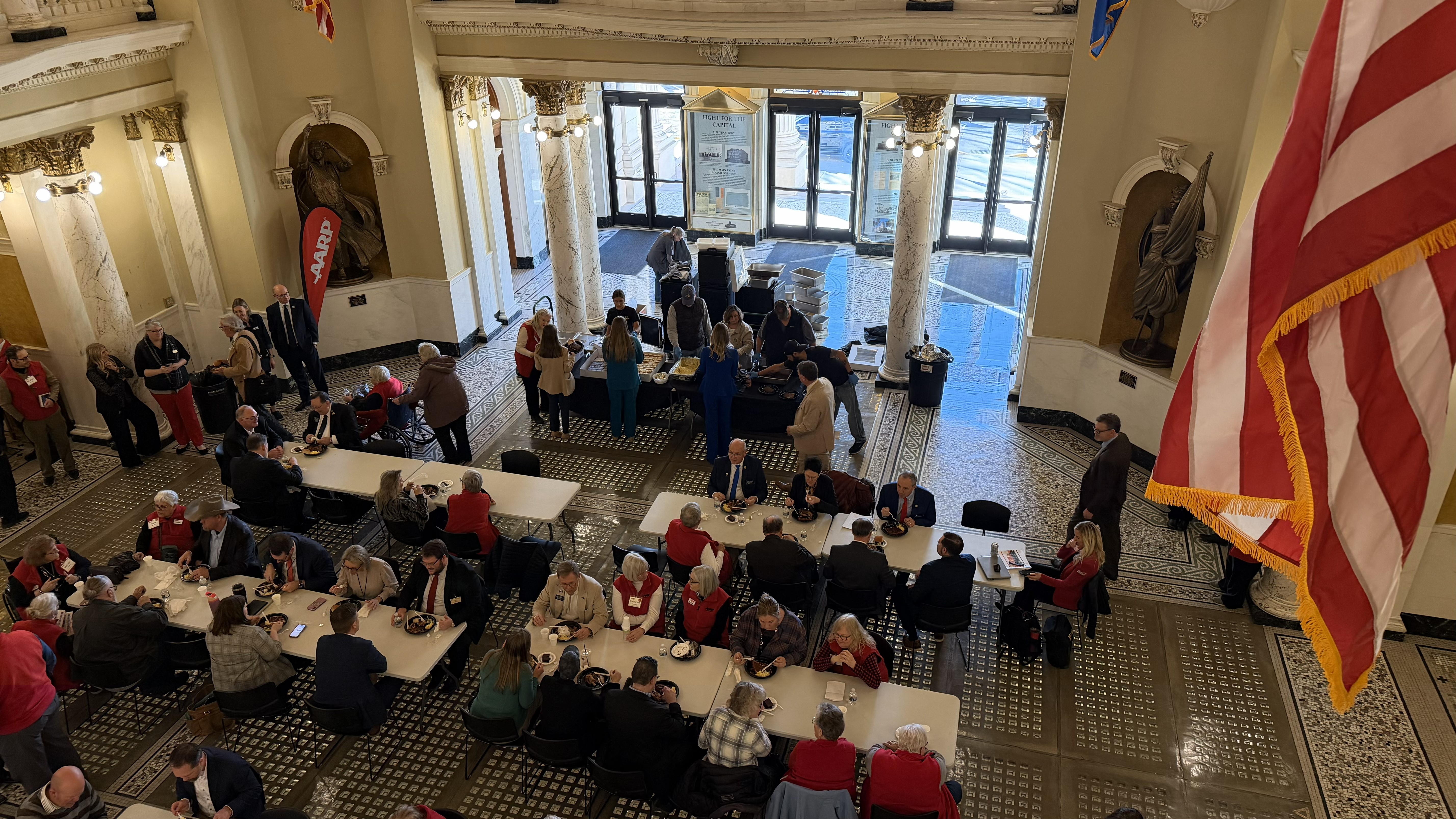 AARP SD volunteers sitting at tables in the SD Capitol Rotunda hosting a lunch with legislators.