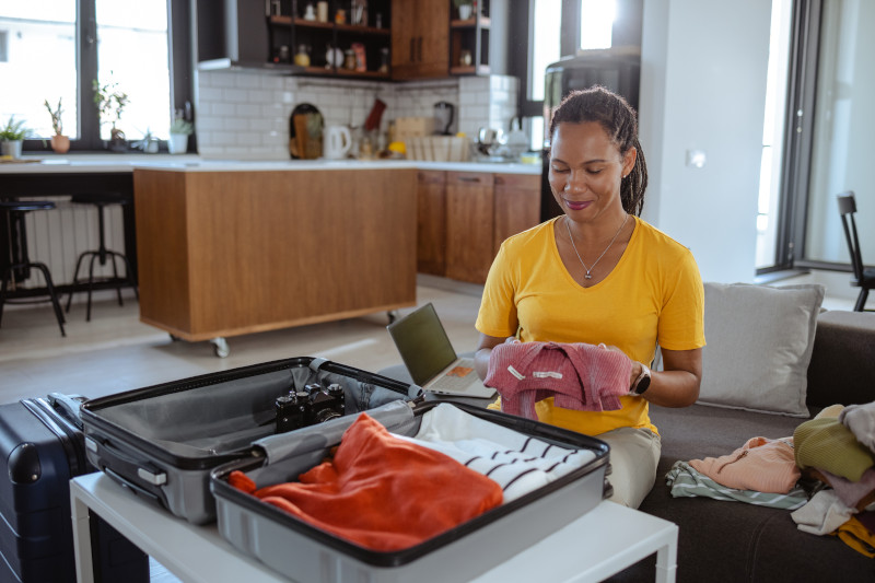 African American woman packing suitcase at home for journey