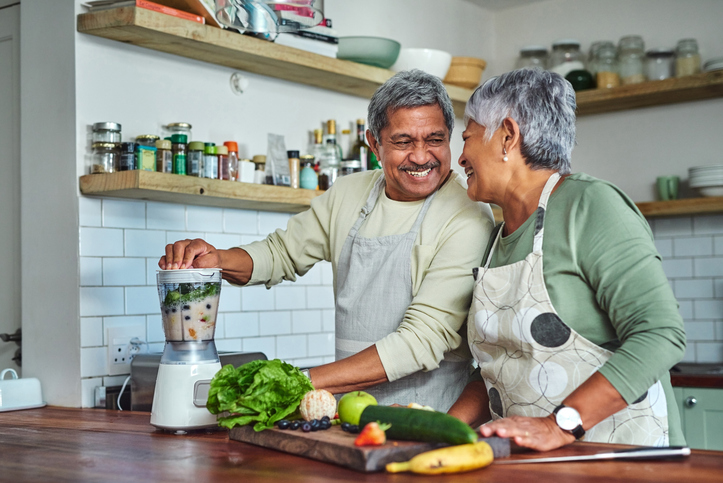 Cheerful senior couple preparing healthy meal using online recipe