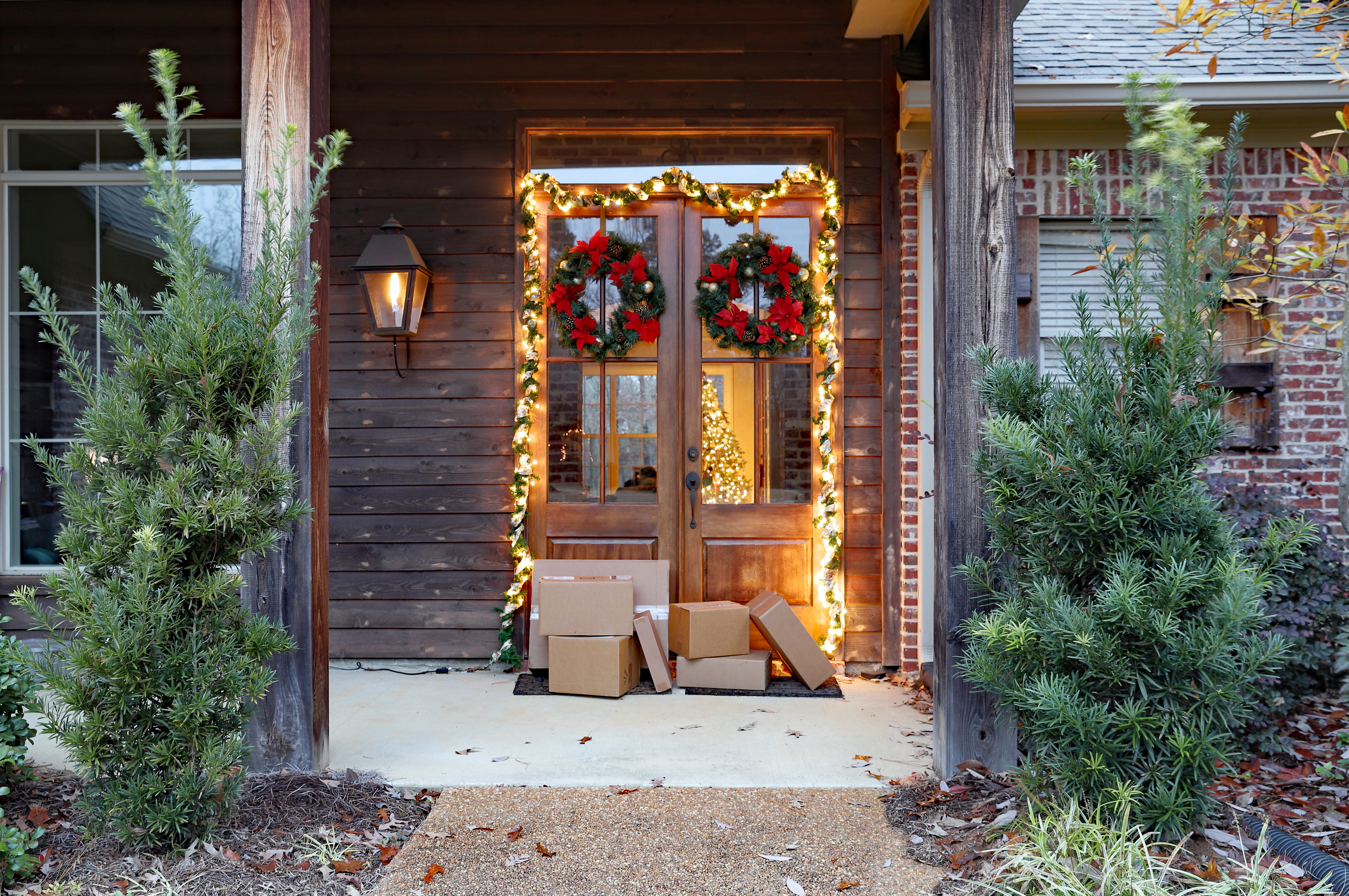 Shipping boxes near front door during holiday season, with Christmas lights