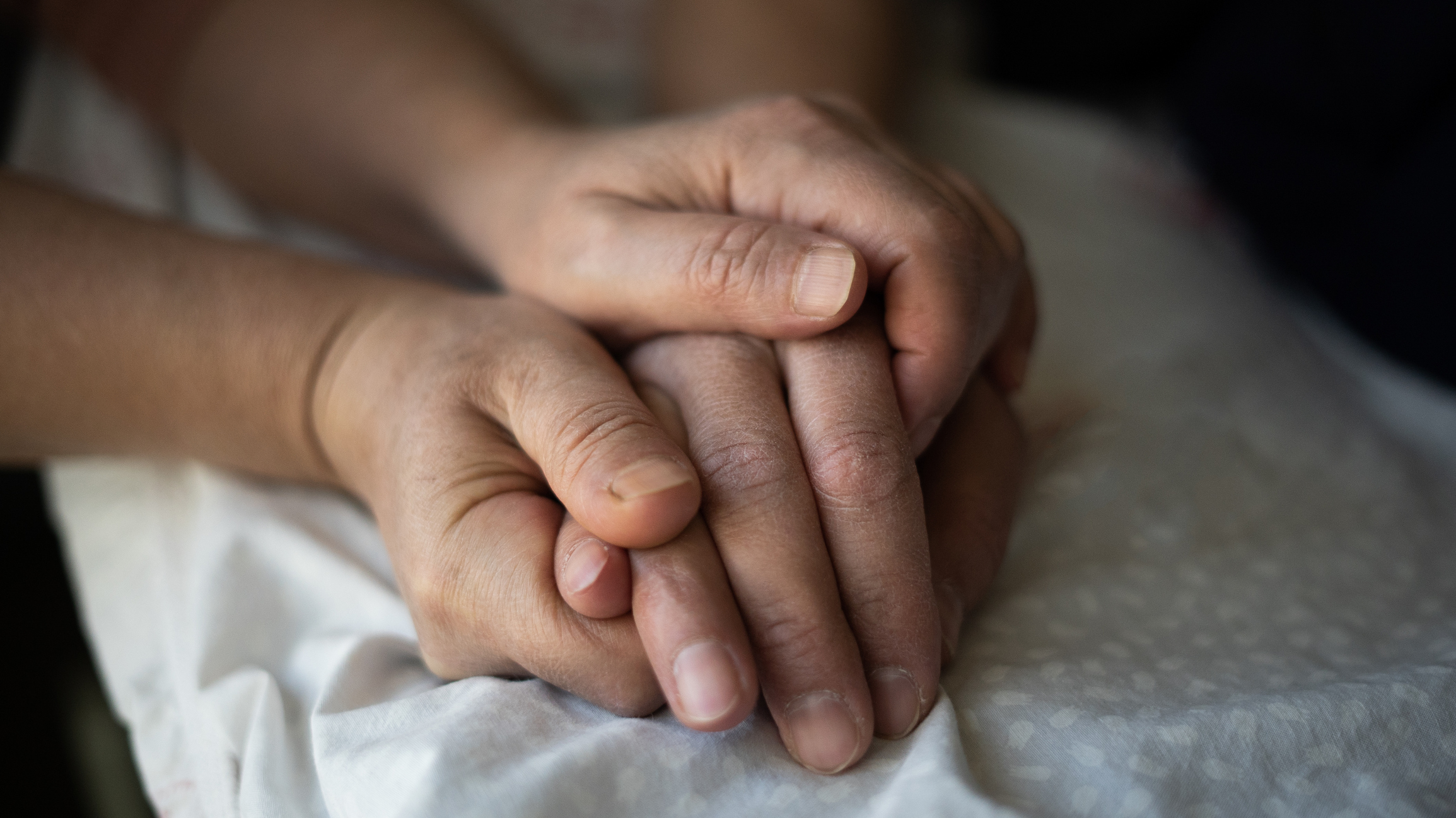 Woman holding the hand of her hospitalized husband