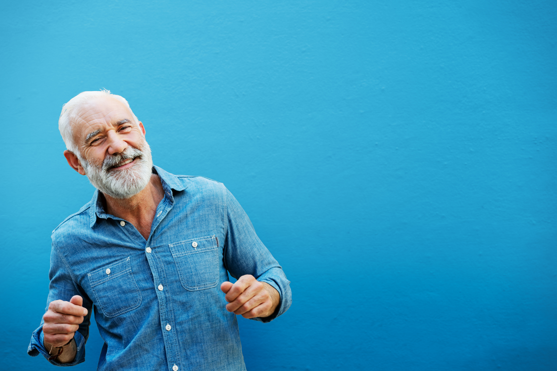 Happy man dancing next to blue wall, outside