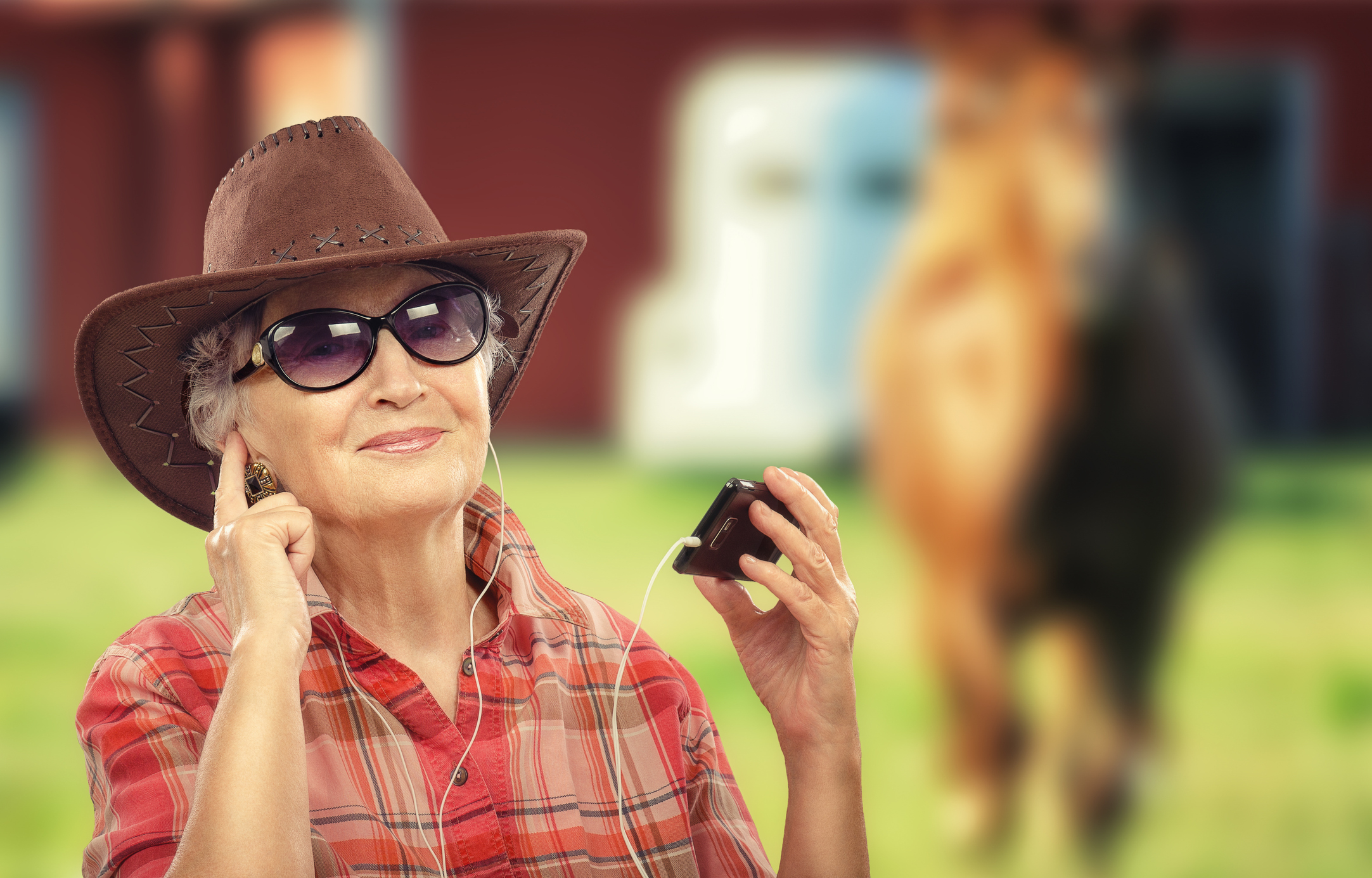 Aged cowgirl listening music with smart phone