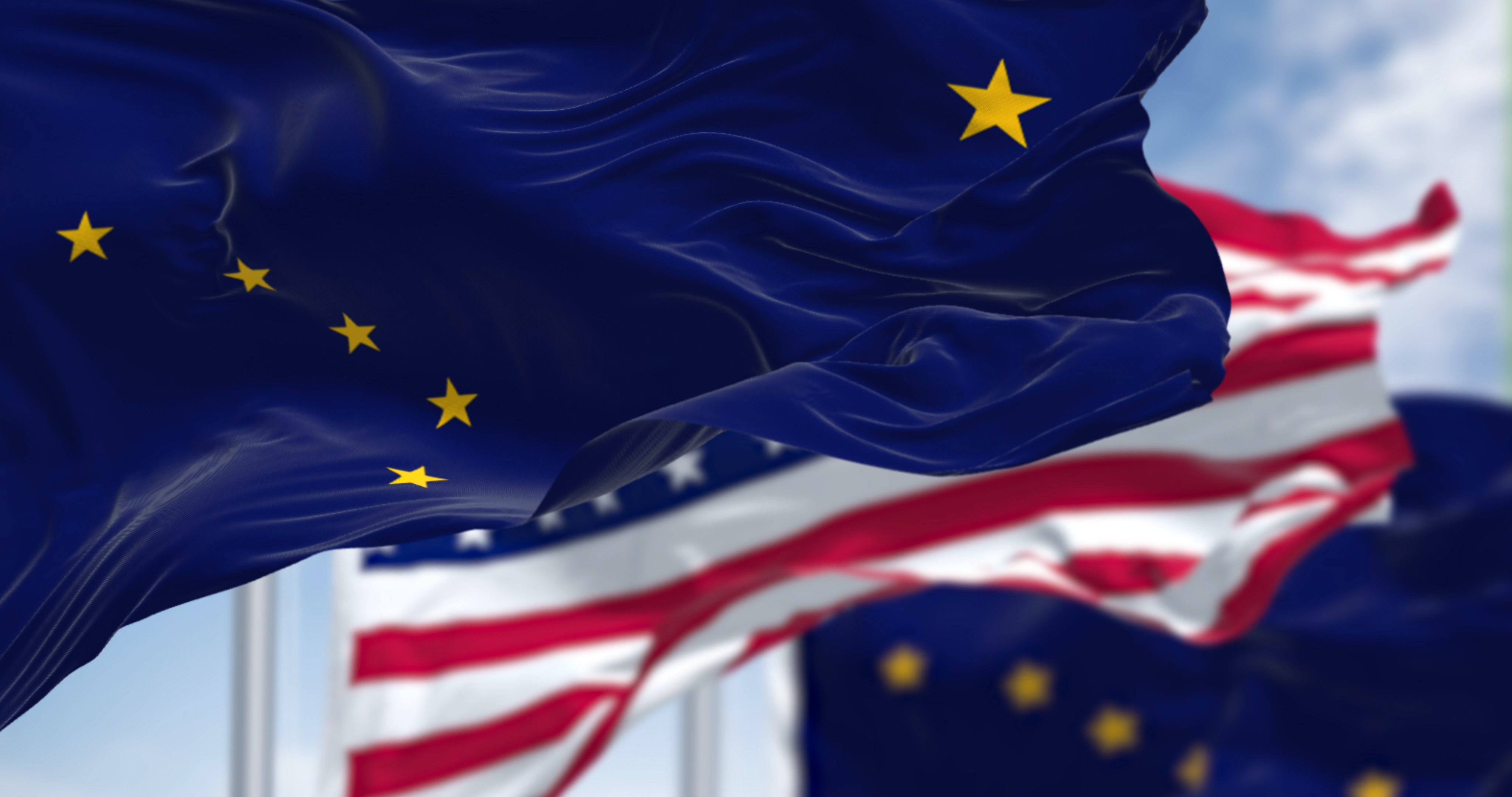 The flags of the Alaska state and United States waving in the wind.