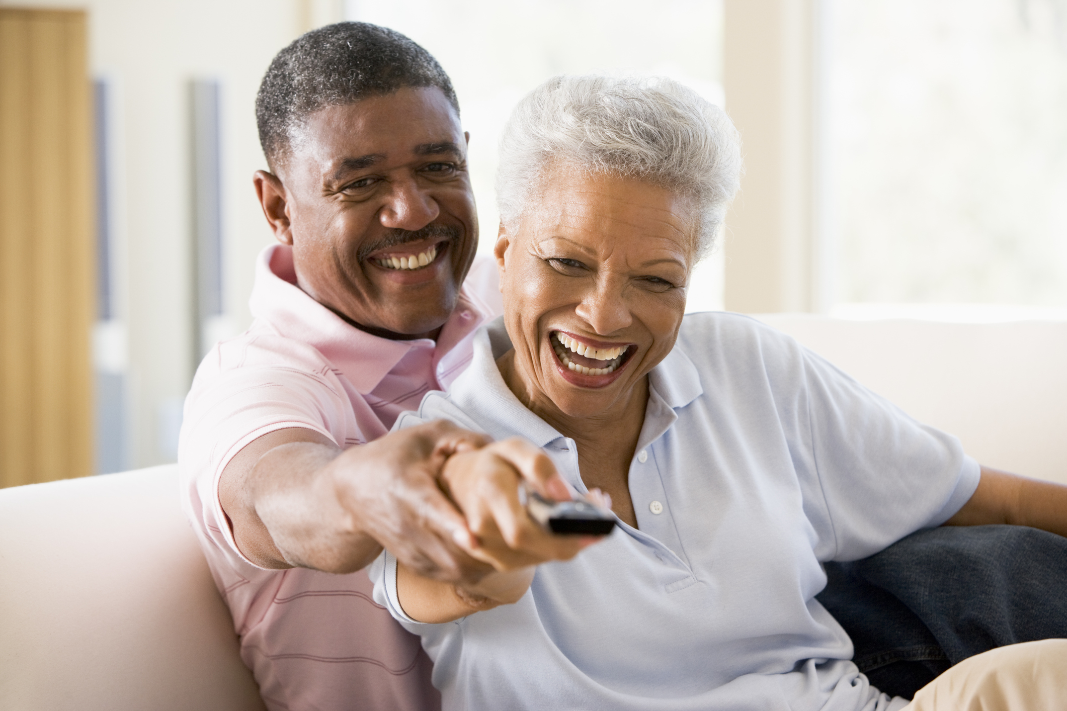 Mature couple sitting on a sofa using a tv remote control