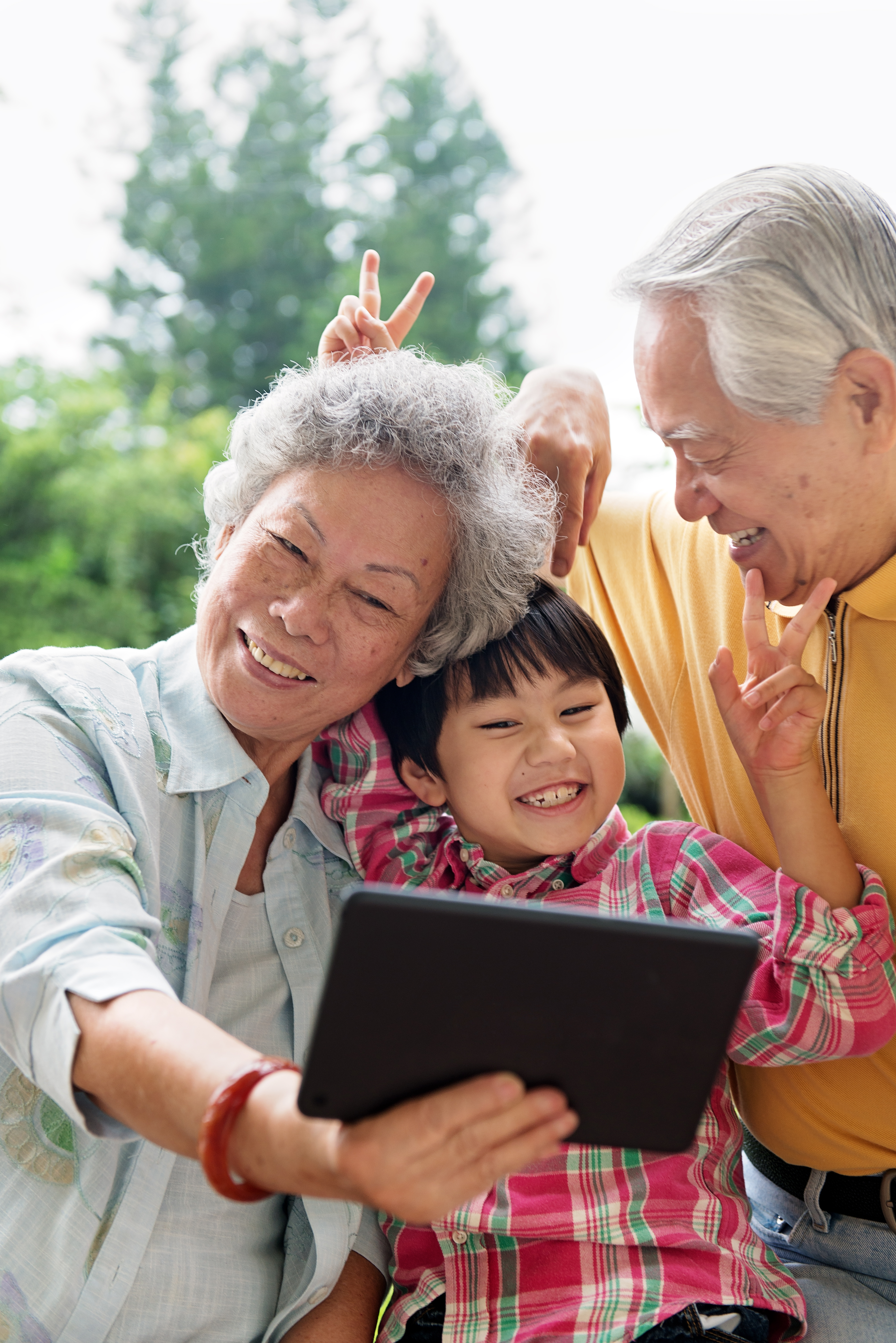 Grandson and grandparents taking selfie with digital tablet