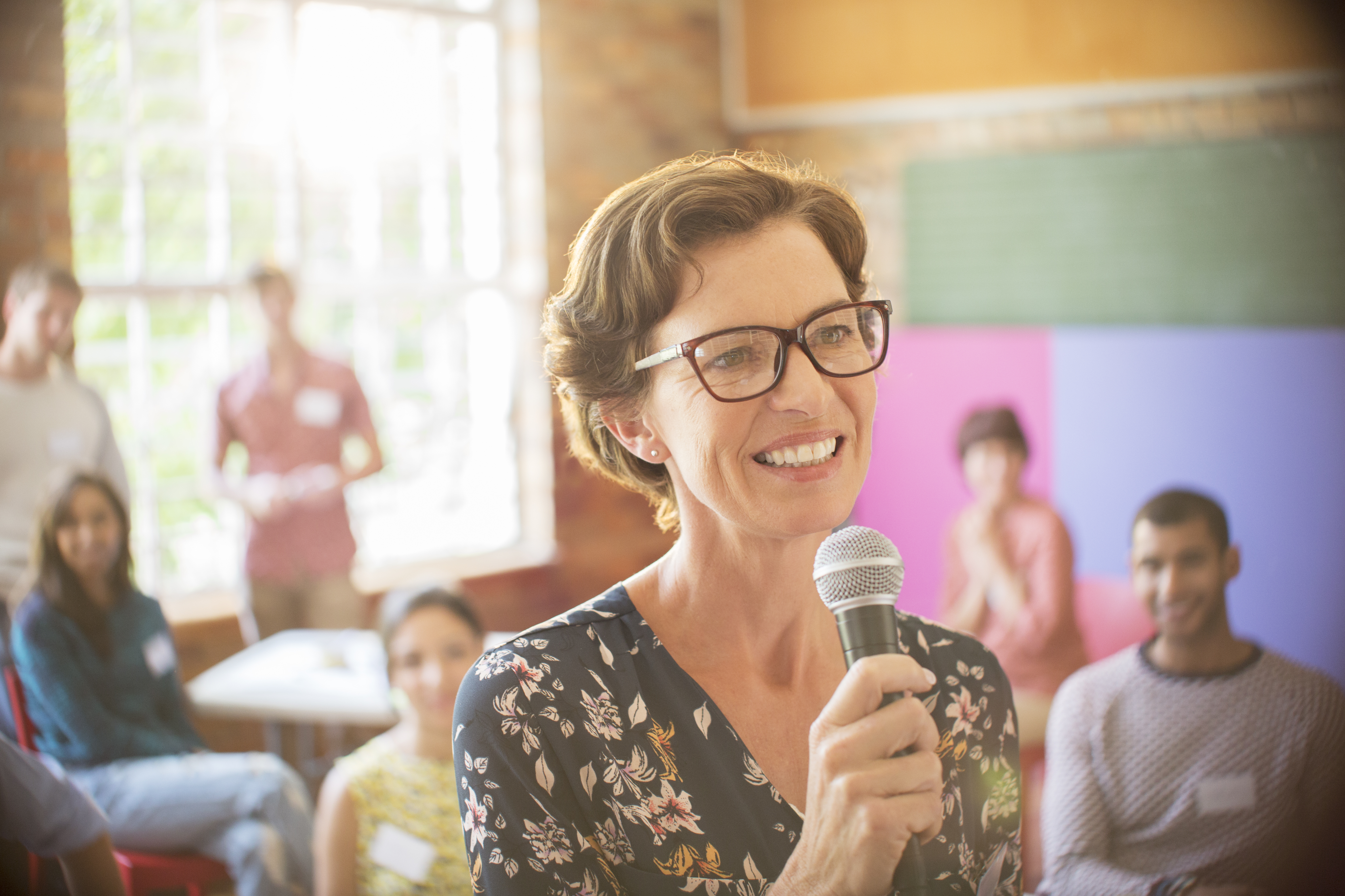 Audience behind smiling speaker with microphone at community center