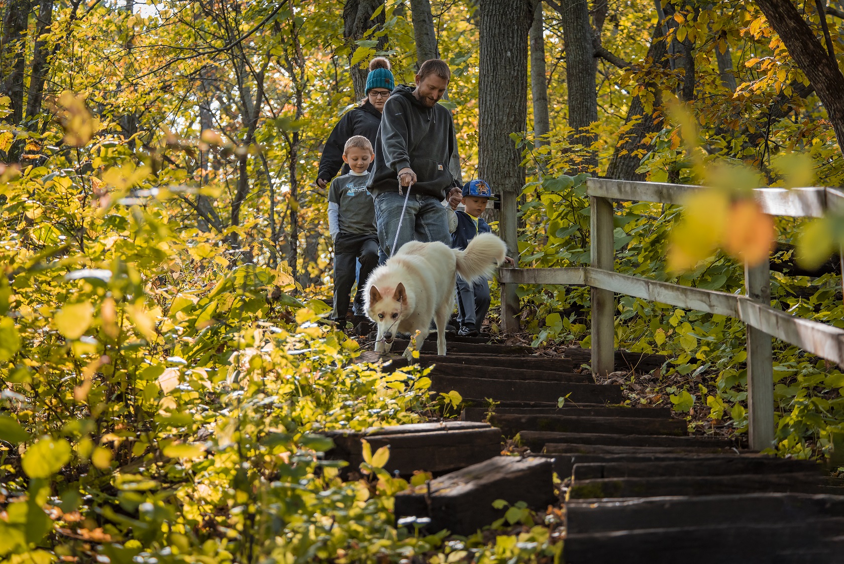 Family and their dog going down wood stairs along a hiking trail in Sica Hollow State Park in South Dakota.