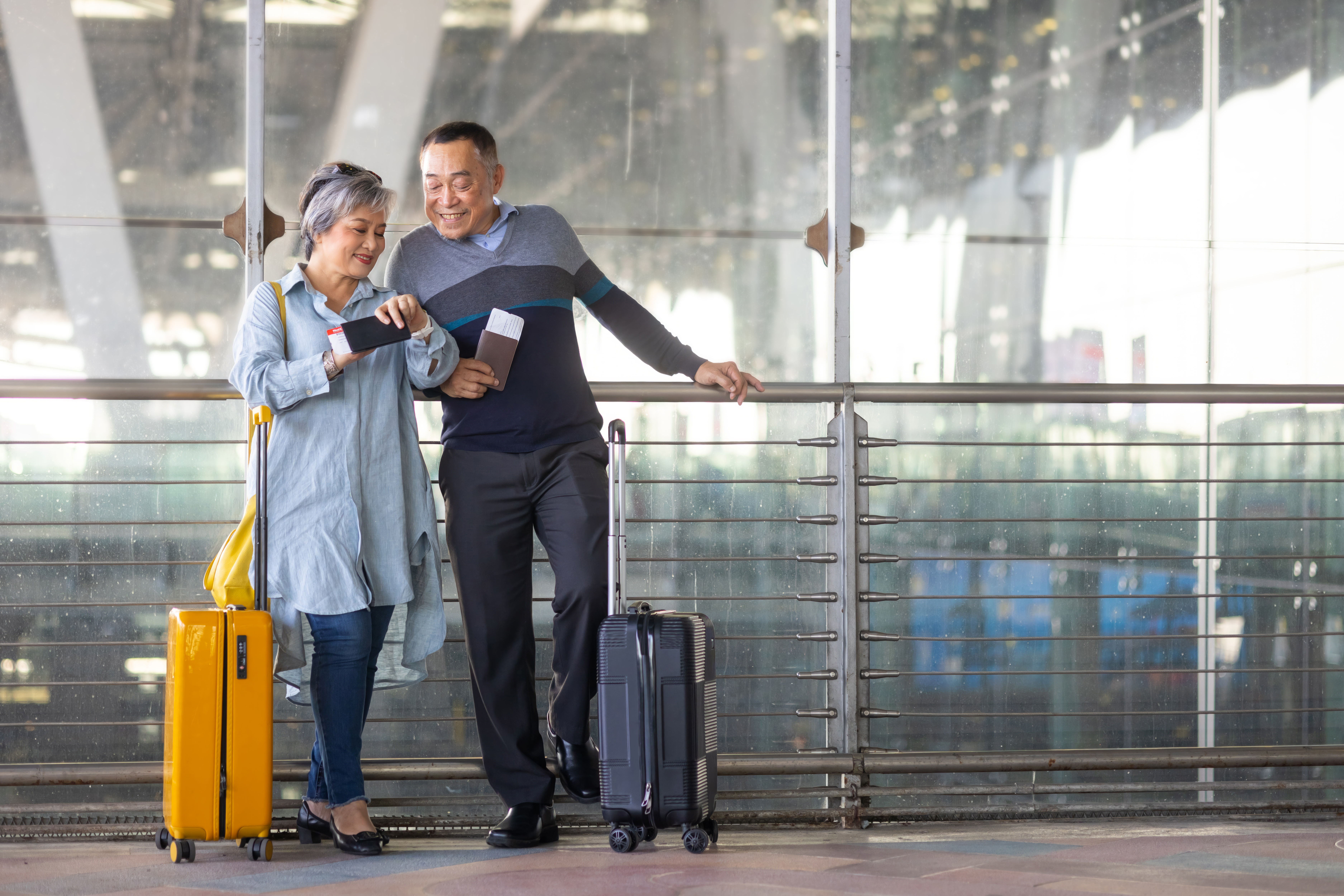 Portrait of Asian senior couple holding passport in Airport Terminal.