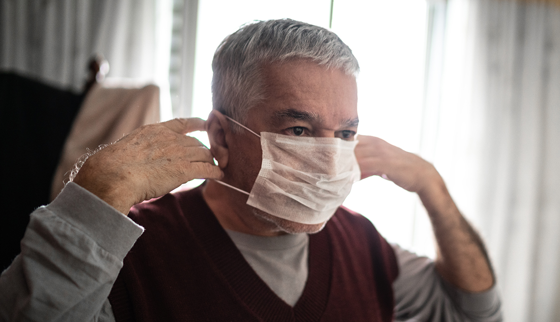 Senior man putting on a protective mask for coronavirus at home