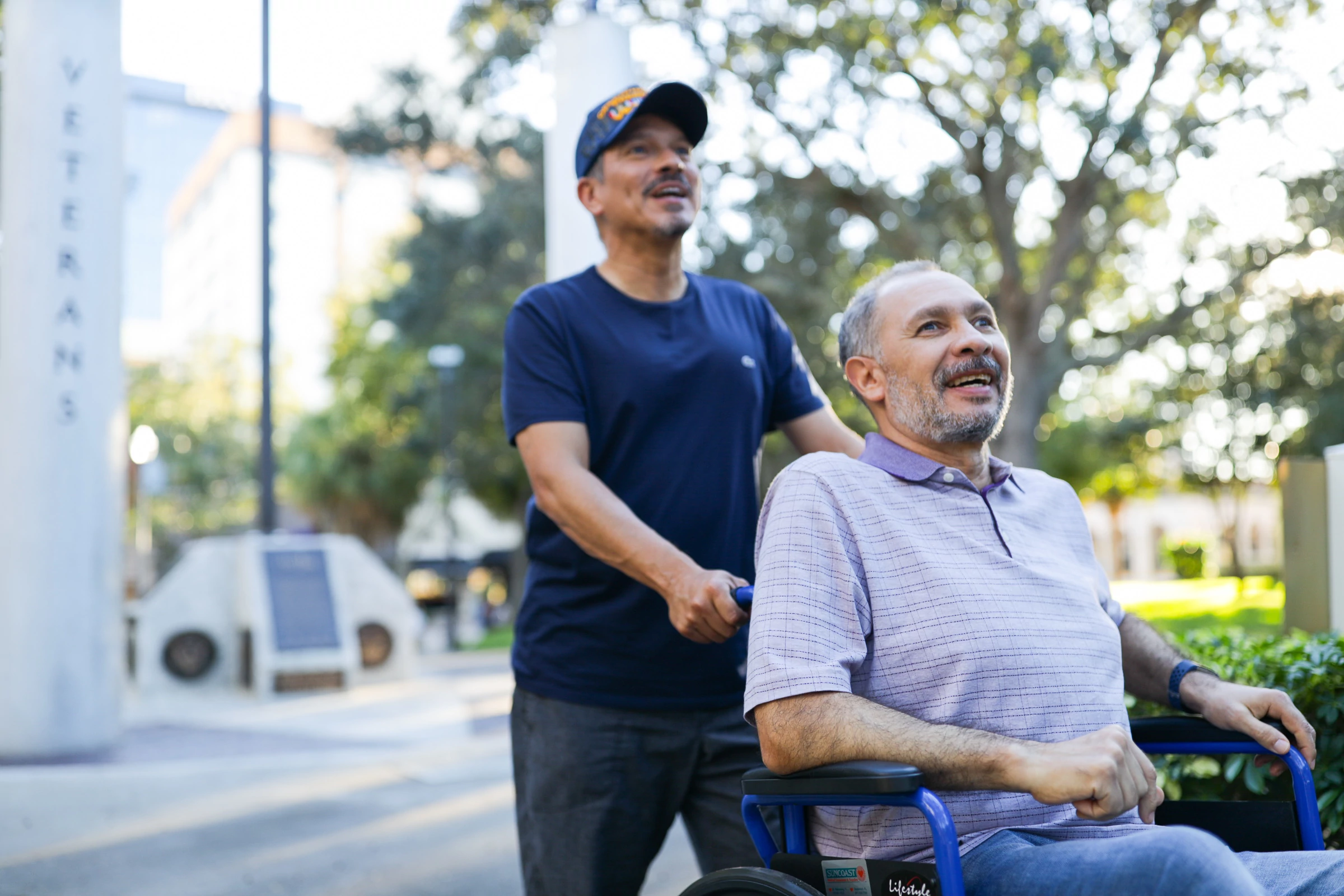 veteran male caregiver pushing male veteran in wheelchair