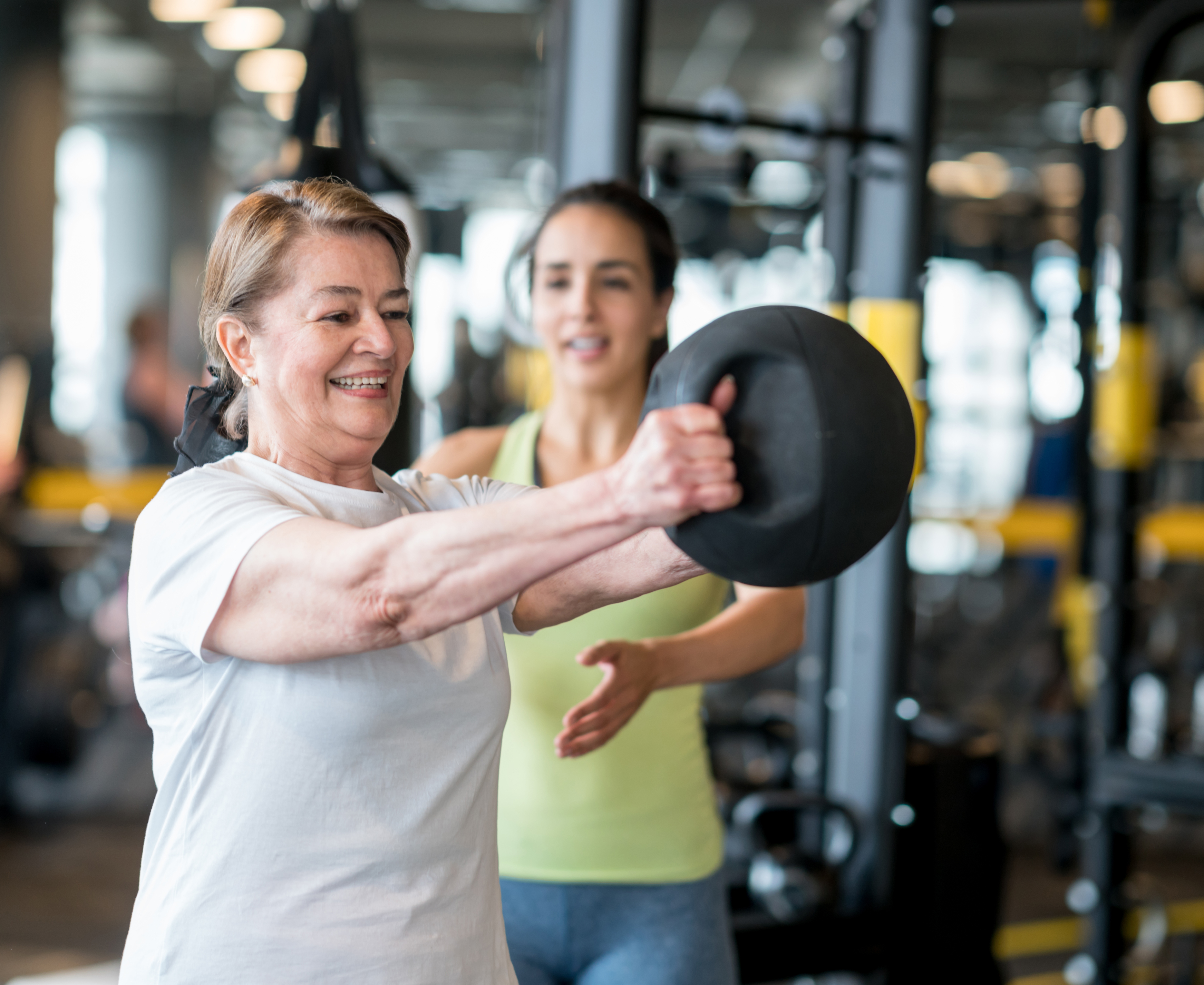 Happy adult woman exercising at the gym with her coach